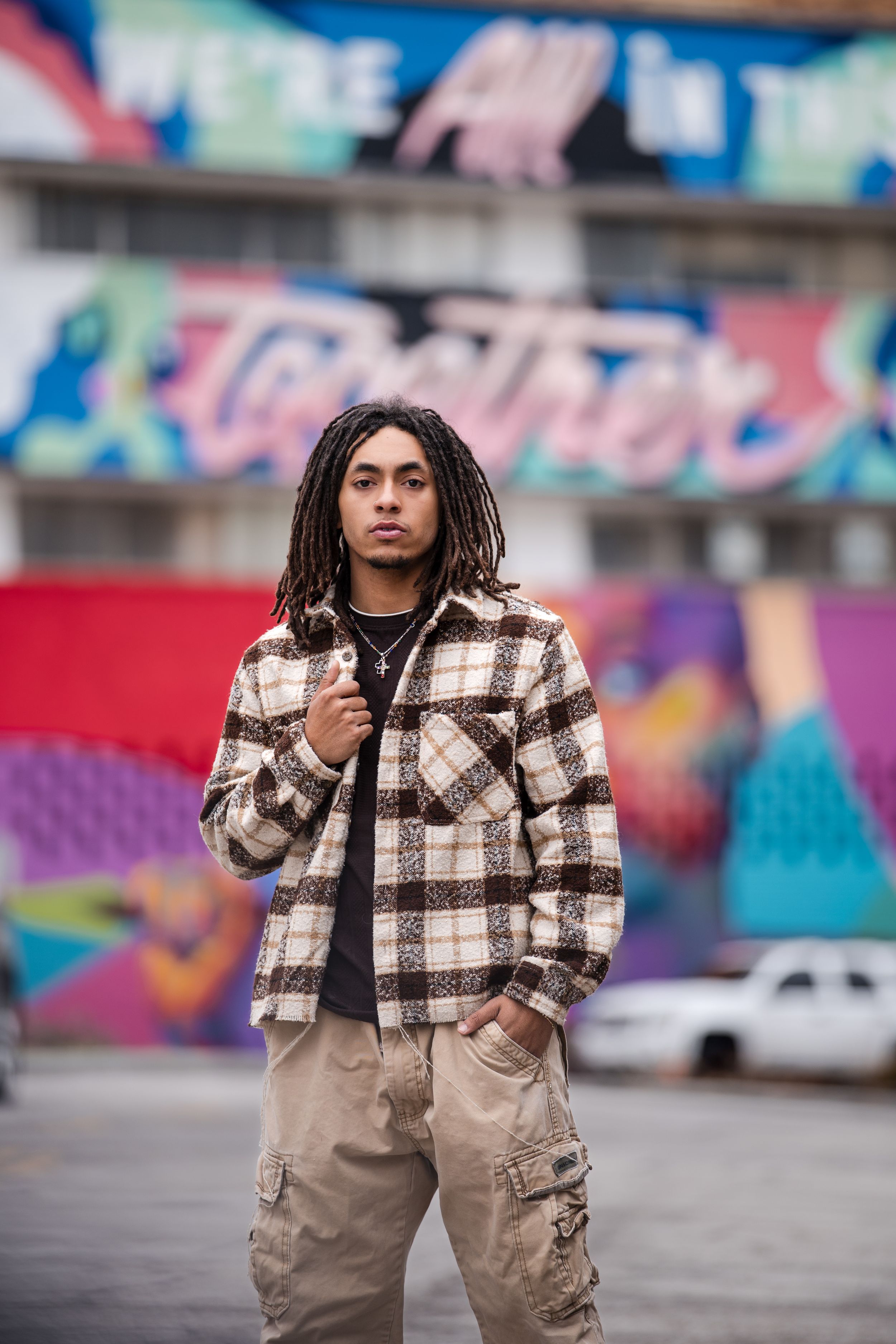 Street style portrait with colorful mural backdrop and casual winter outfit.