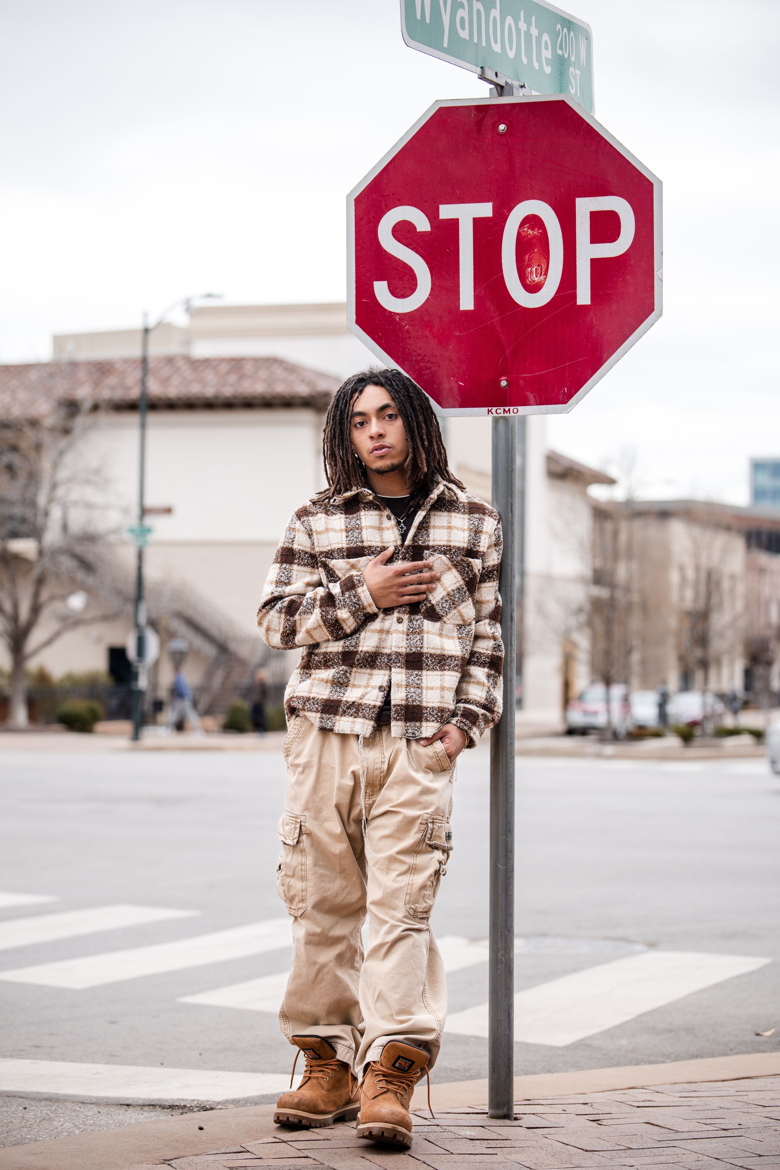 Street fashion photography with stop sign and urban intersection backdrop.