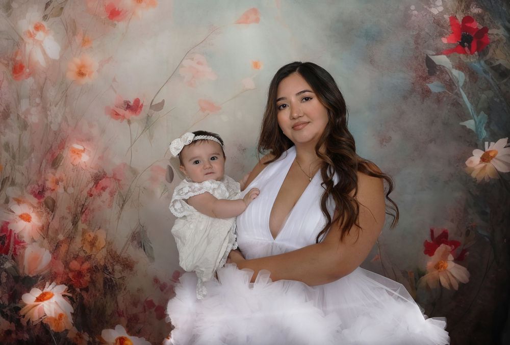 Family maternity session with soft lighting and floral backdrop in white dresses.