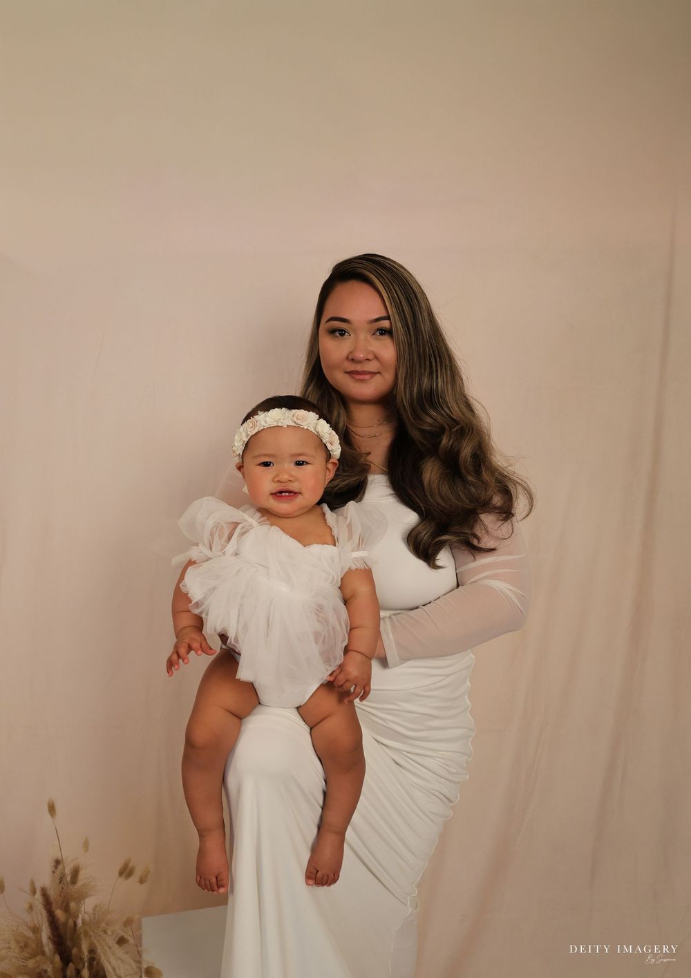 A series of intimate studio portraits showing tender moments between parent and baby in white outfits against a neutral backdrop.