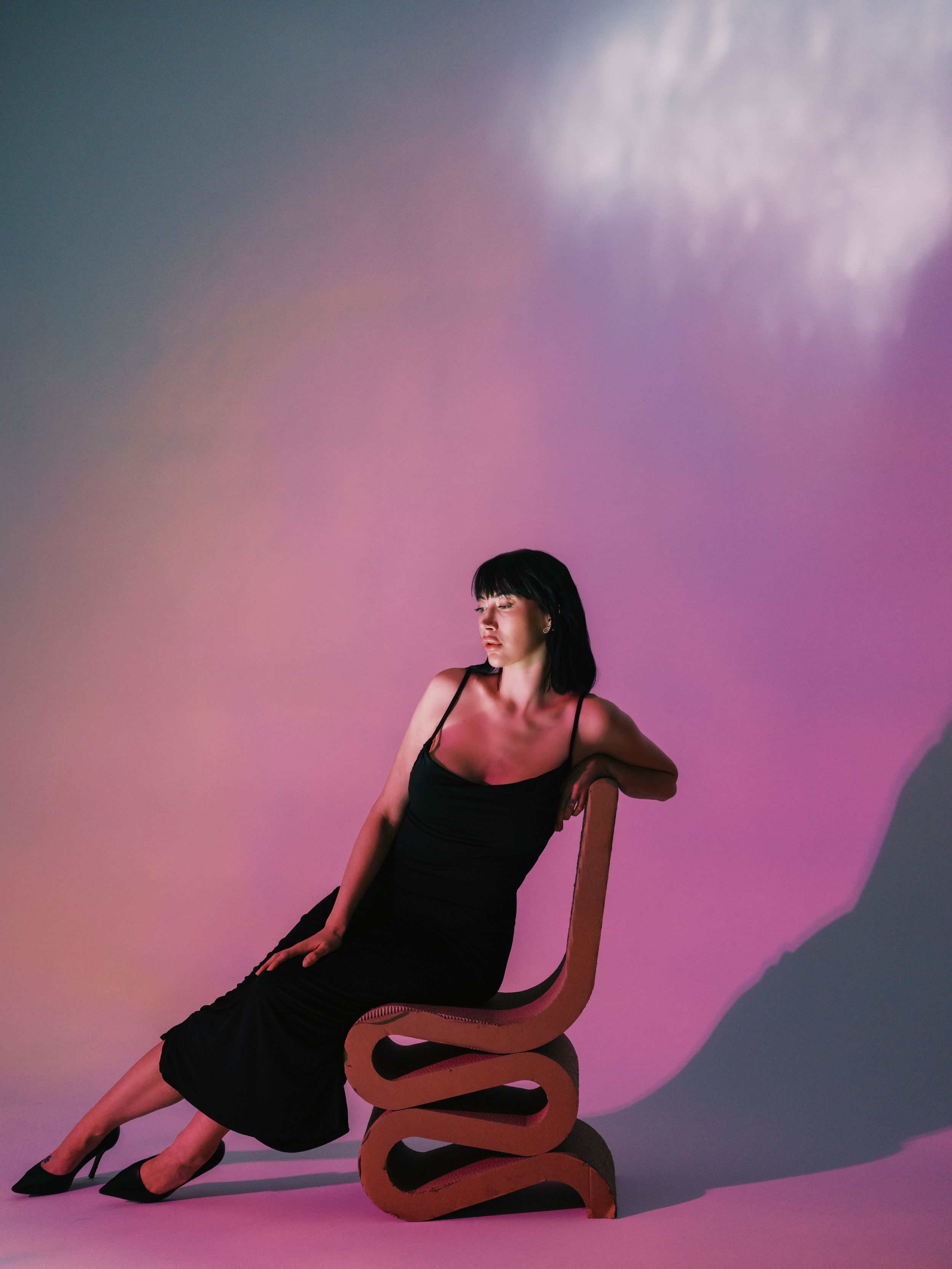 Modern fashion photo with sculptural poses against a pink and purple gradient backdrop.
