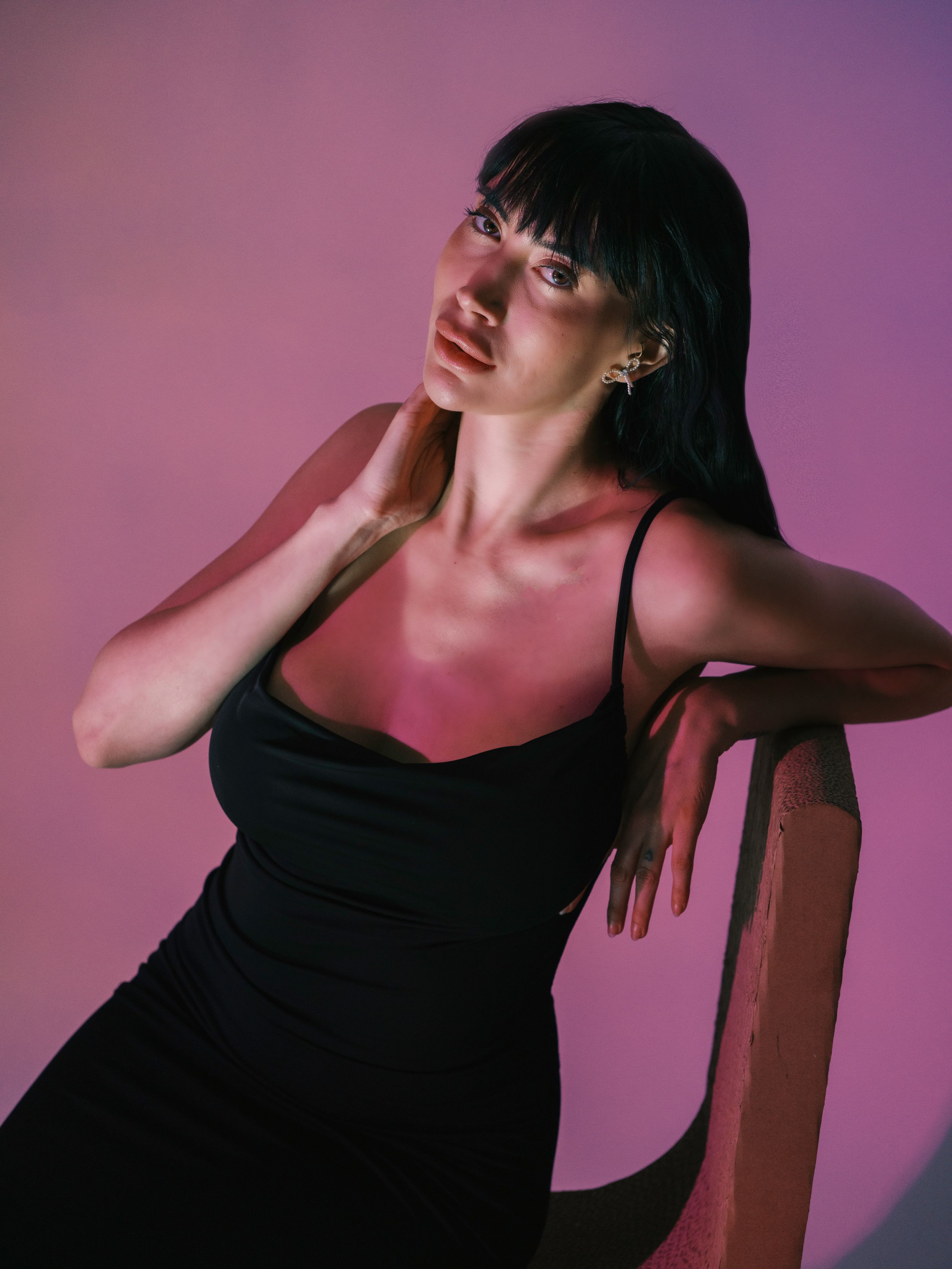 Dramatic fashion portrait with moody lighting against a purple gradient background.