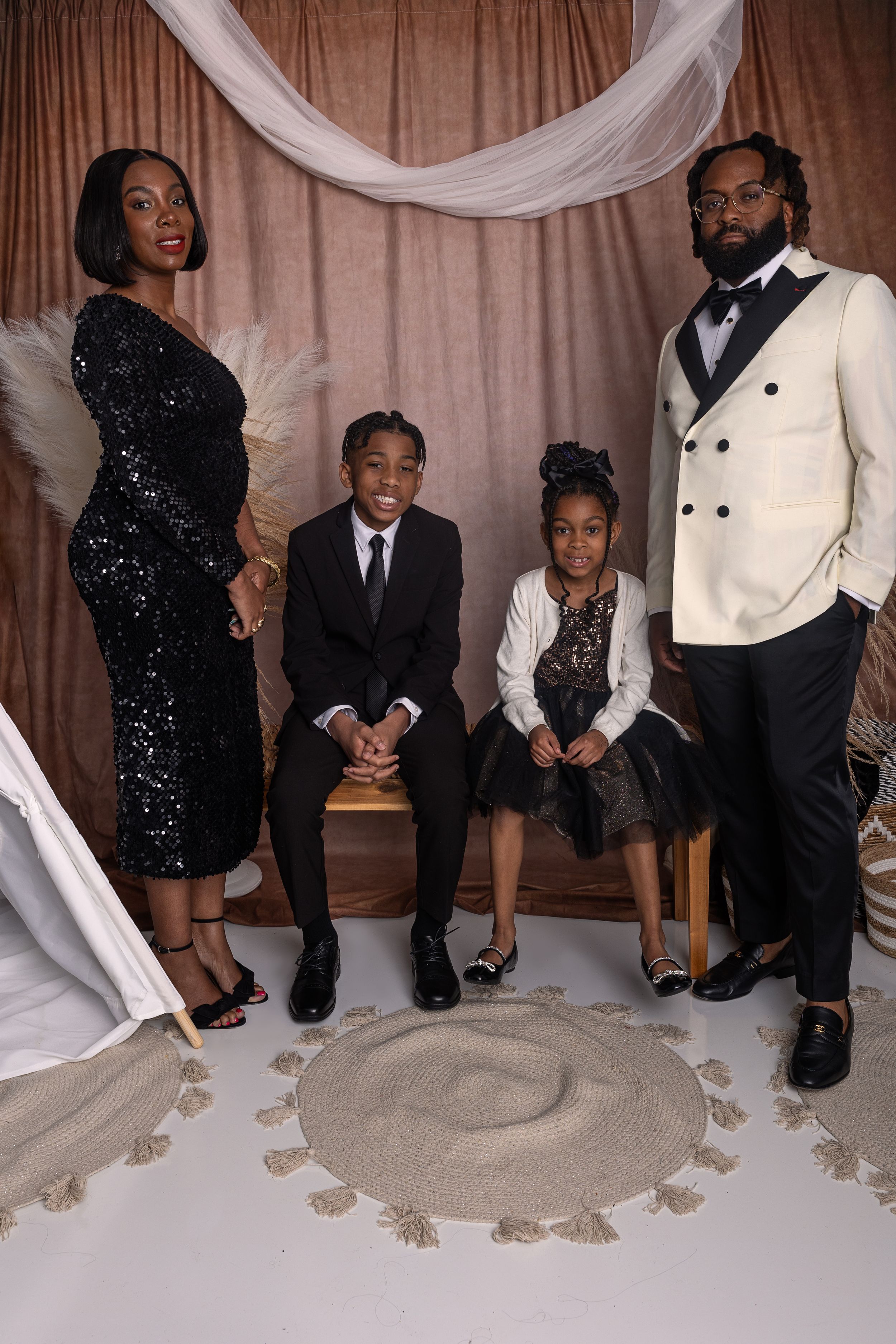 A family dressed elegantly poses for a formal portrait with a draped backdrop and decorative elements.
