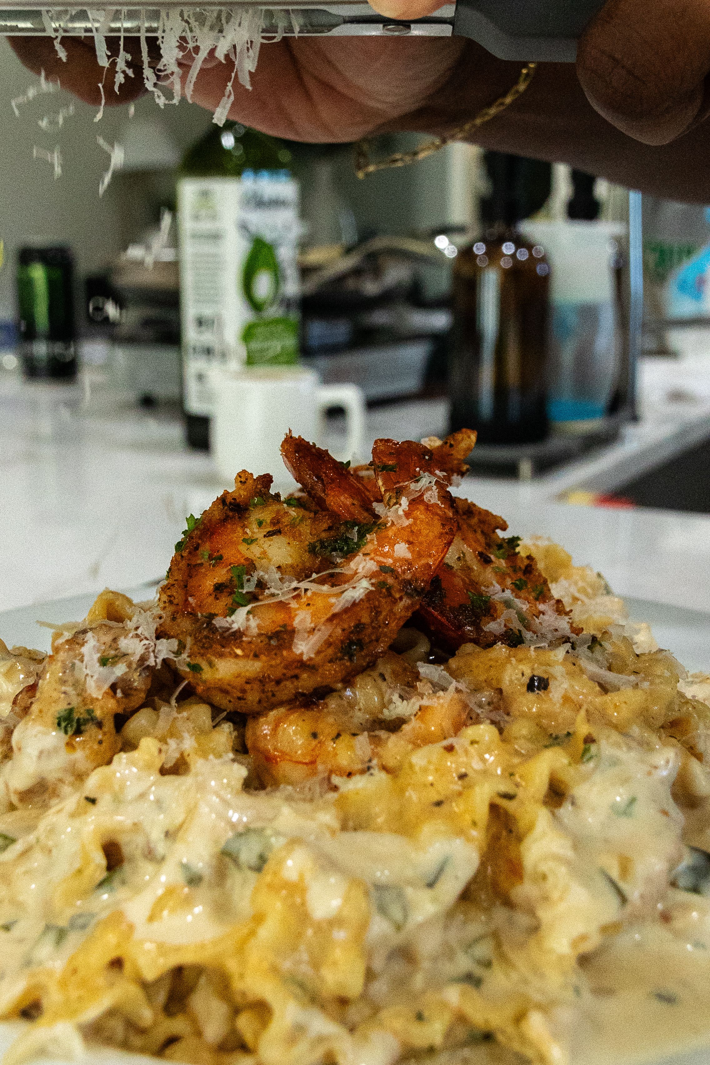 Grilled shrimp served over creamy pasta with parmesan cheese and herbs in a restaurant setting.