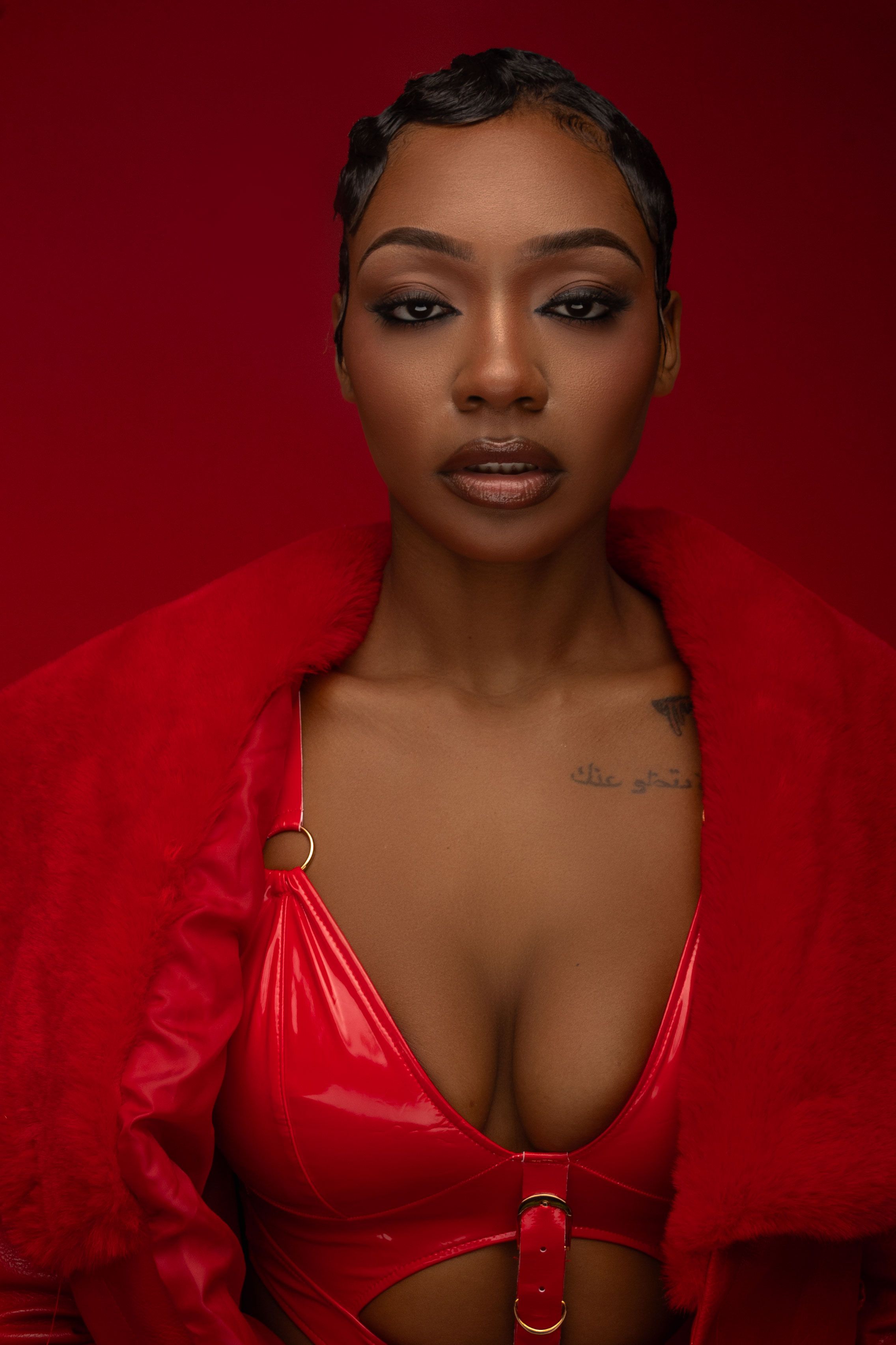 A glamorous portrait against a red backdrop featuring bold red fashion and dramatic makeup.