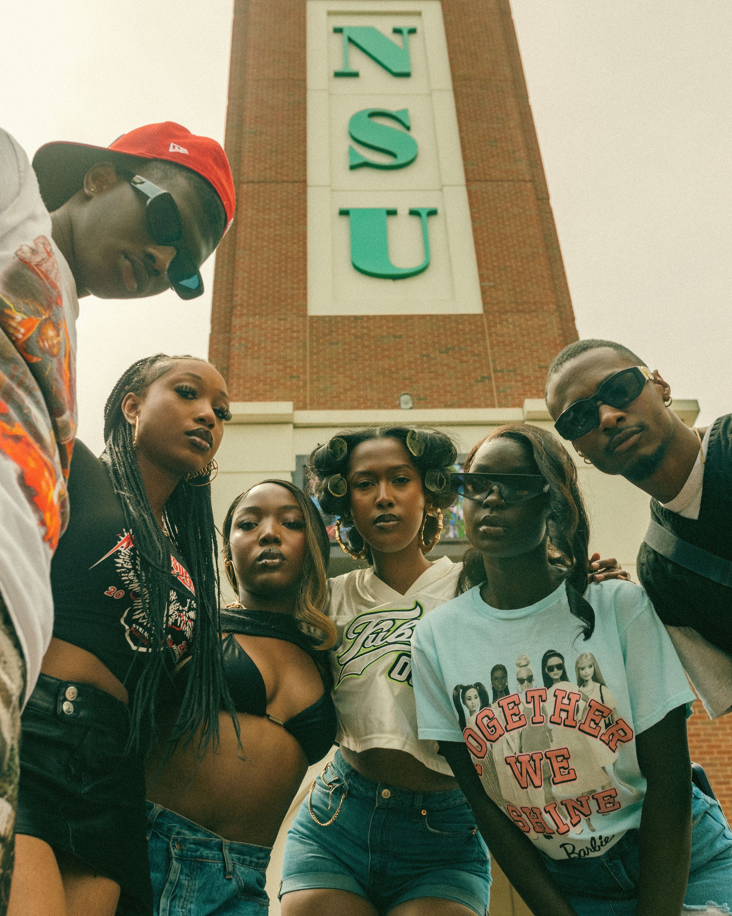 A retro-style photo of college students posing together in front of a building with NSU lettering.