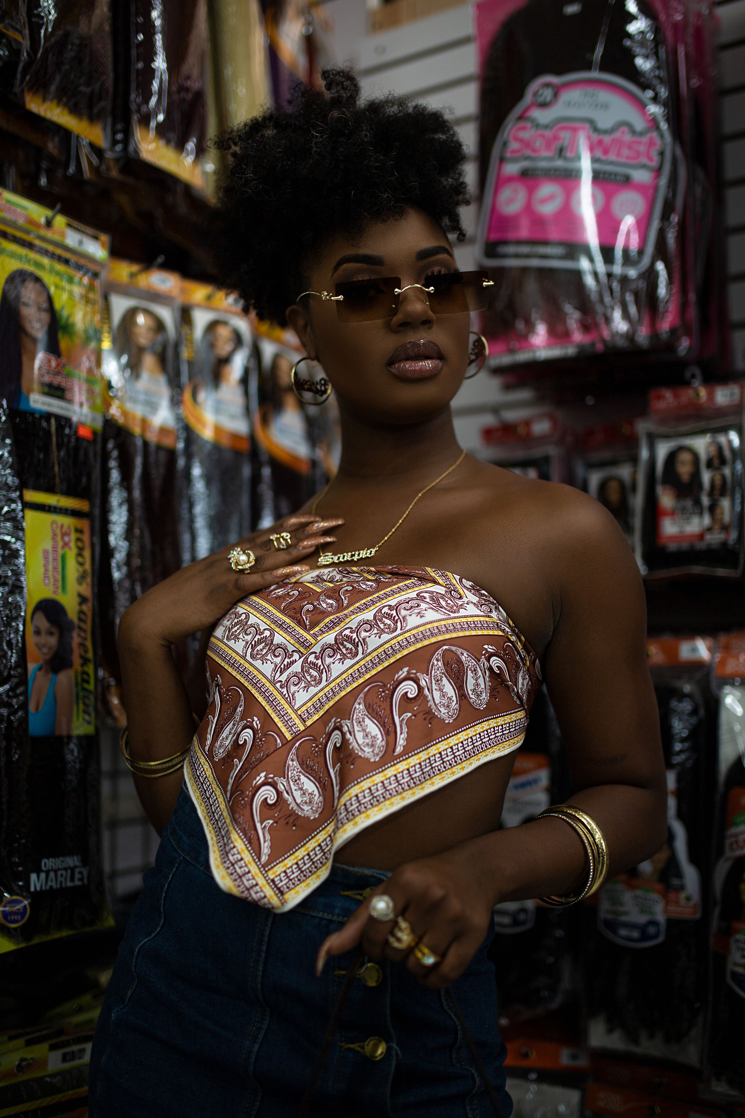 A fashionable look featuring a printed bandana top, dark denim, and stylish sunglasses in a store setting.