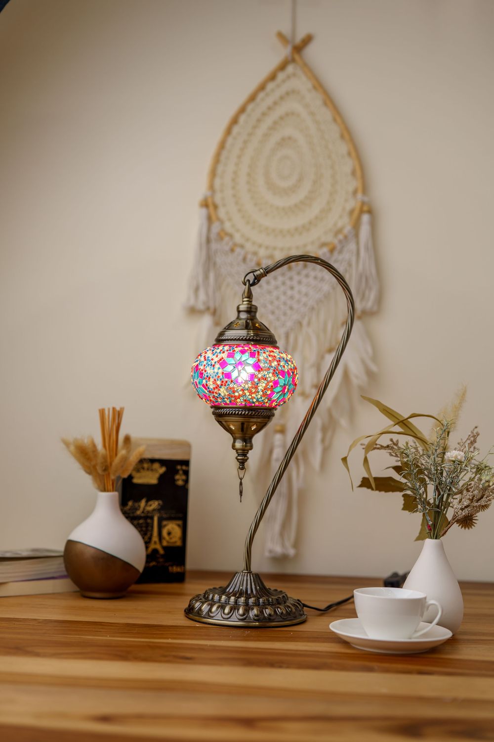 Colorful mosaic table lamp with ornate base sits on wooden desk with dreamcatcher and decorative vases.