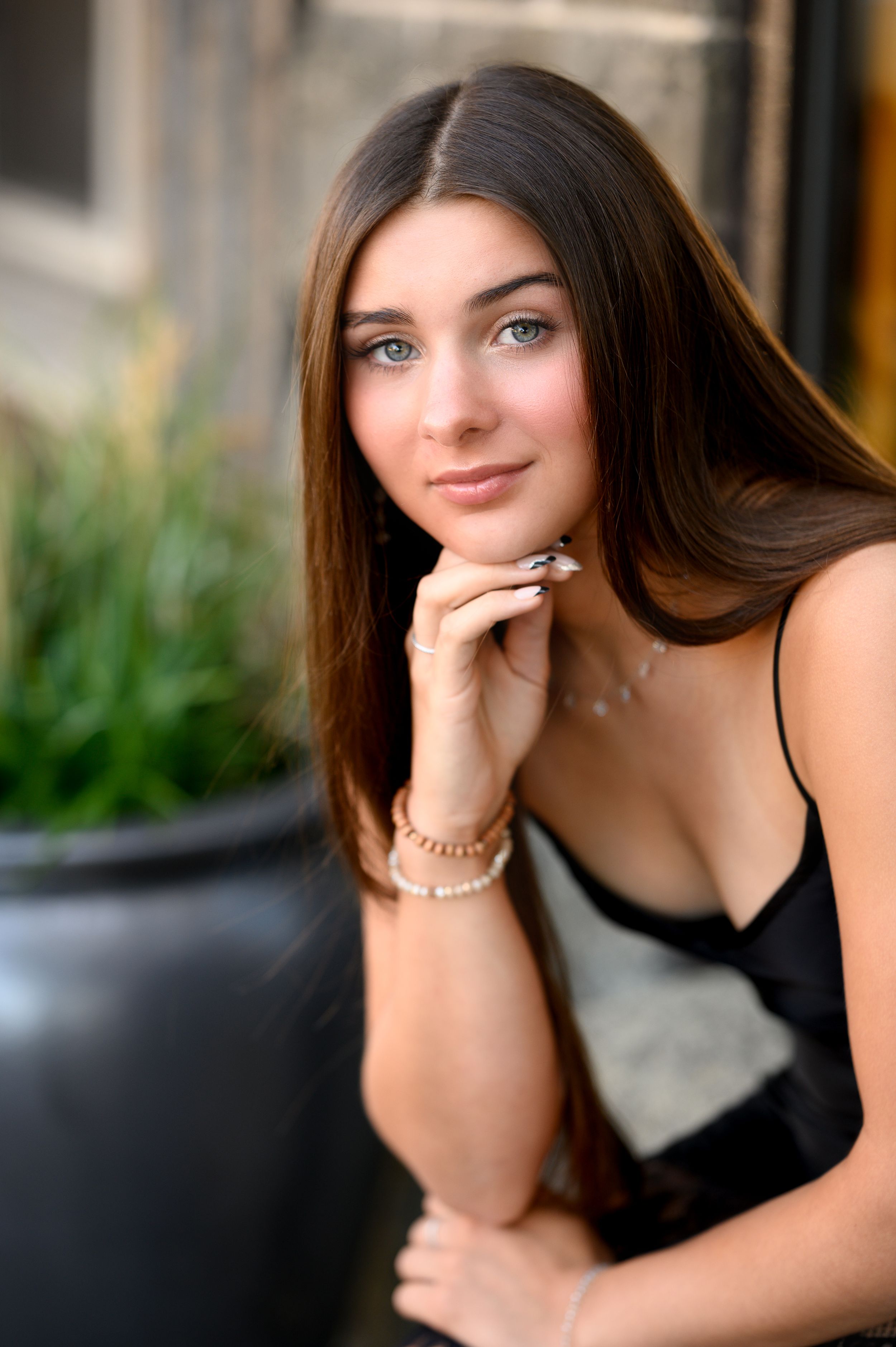 Portrait of someone in black top posing against blurred background.