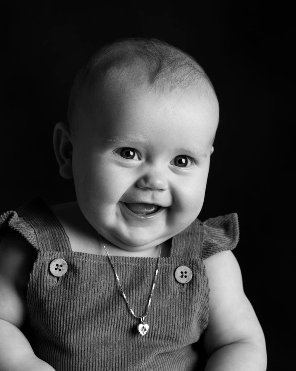 Baby som sitter og smiler under en babyfotografering i et fotostudio i Flekkefjordl