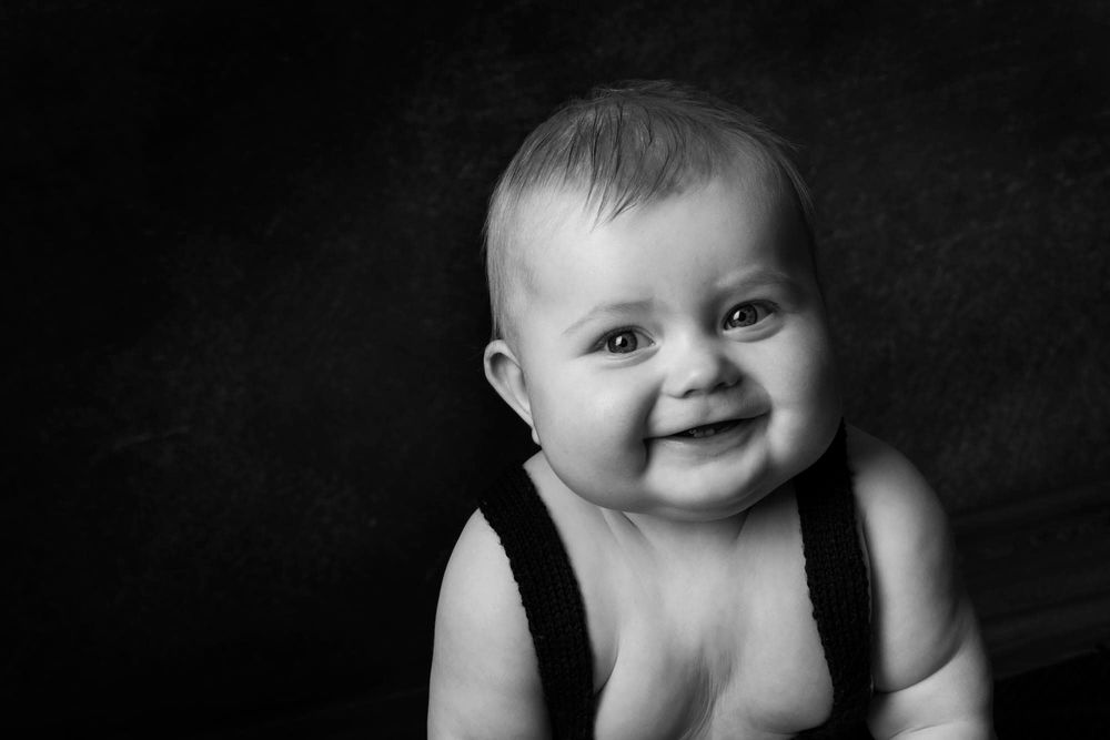 Baby som smiler og ser i kamera i et fotostudio i Mandal
