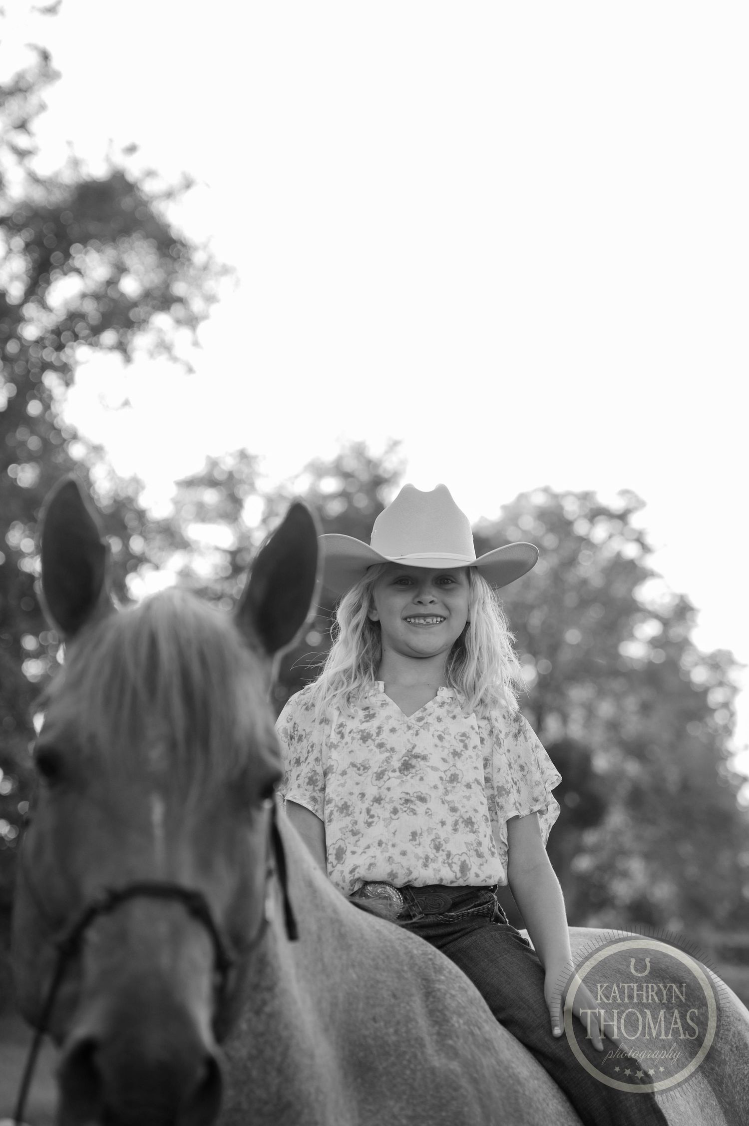 Black and white portrait of a rider on horseback wearing a cowboy hat.