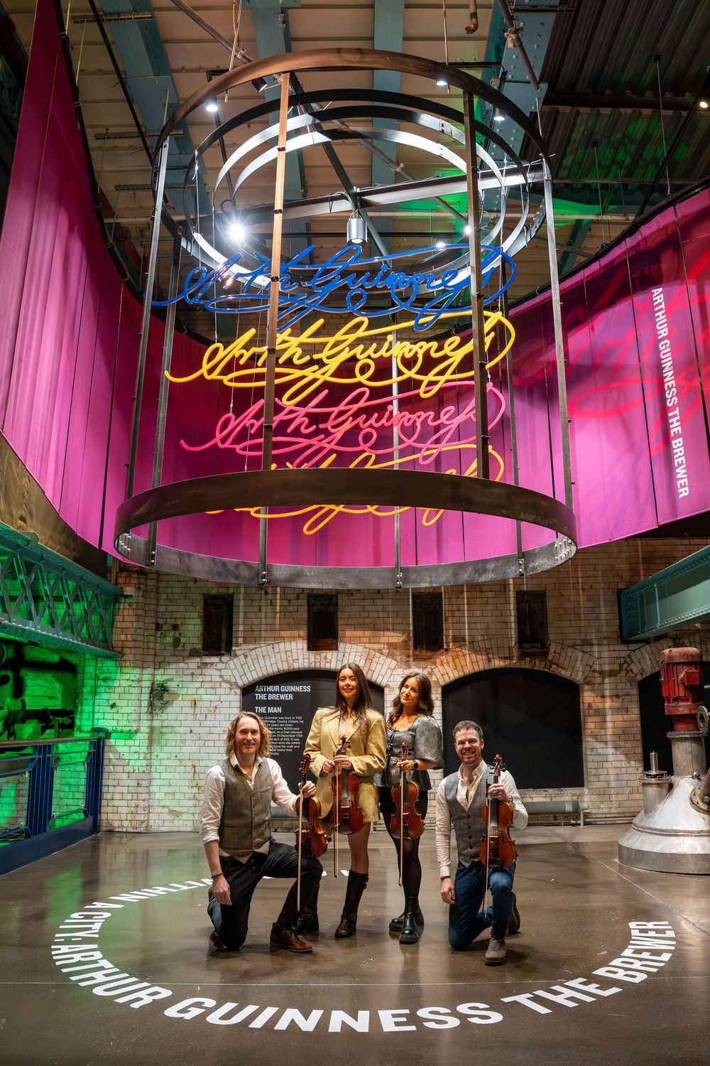 Group enjoying the interactive Guinness brewery tour experience under neon lighting and pink drapes. The Guinness Storehouse, Dublin.