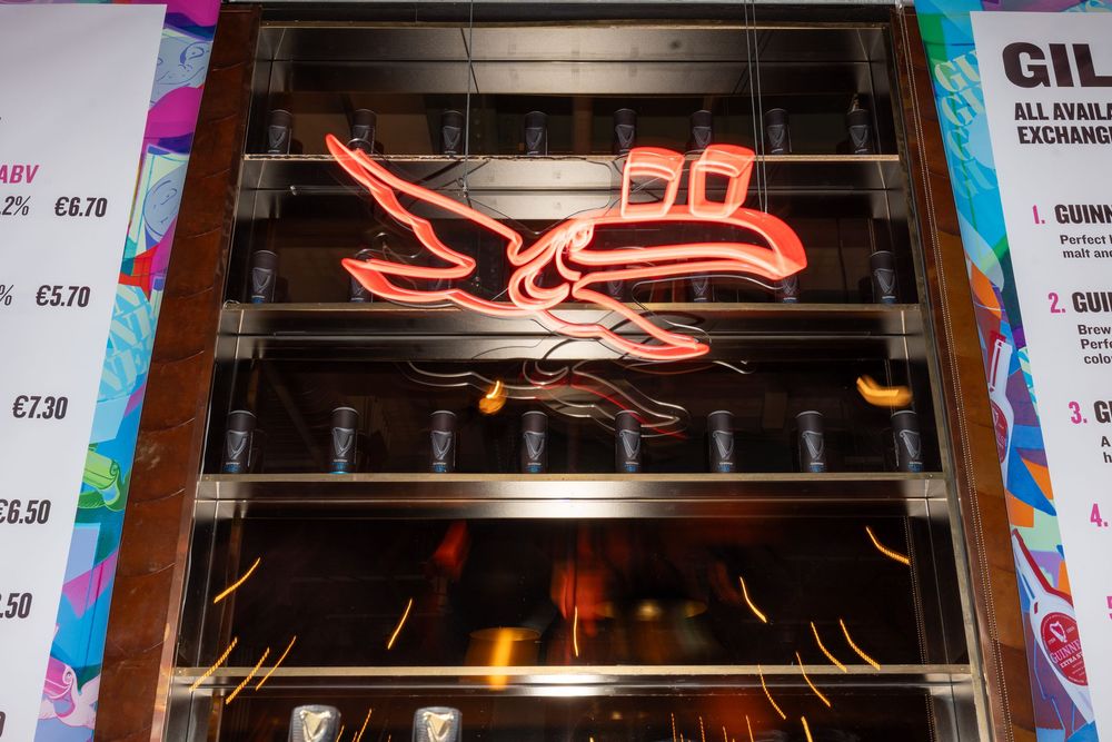 Colorful neon signage illuminates a modern industrial-style venue ceiling.