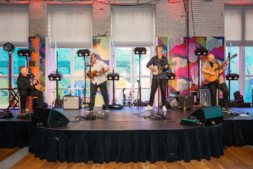 Musicians perform on a stage setup indoors with professional lighting and sound equipment.