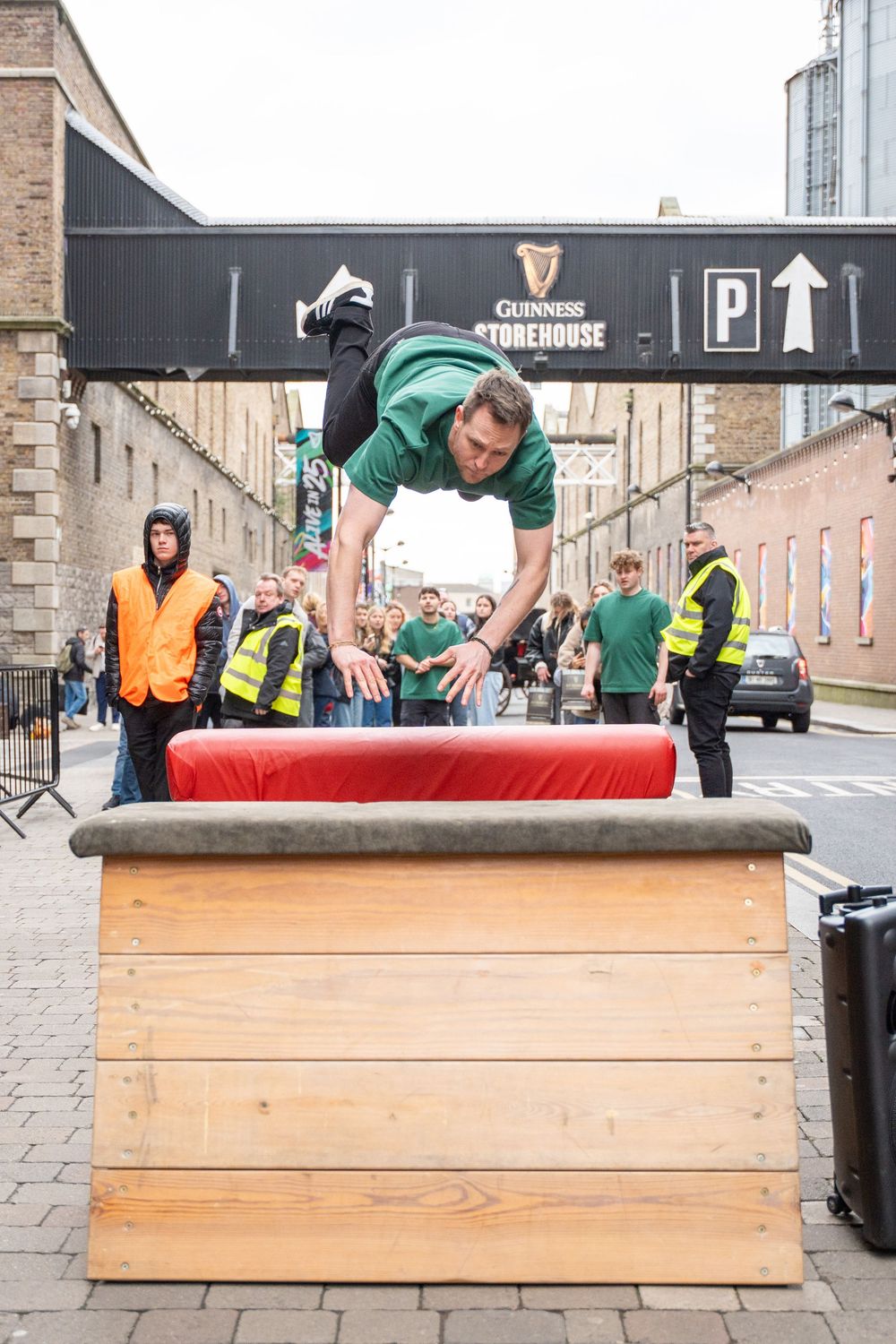 Urban parkour demonstration with participants jumping over wooden platforms in a city setting.