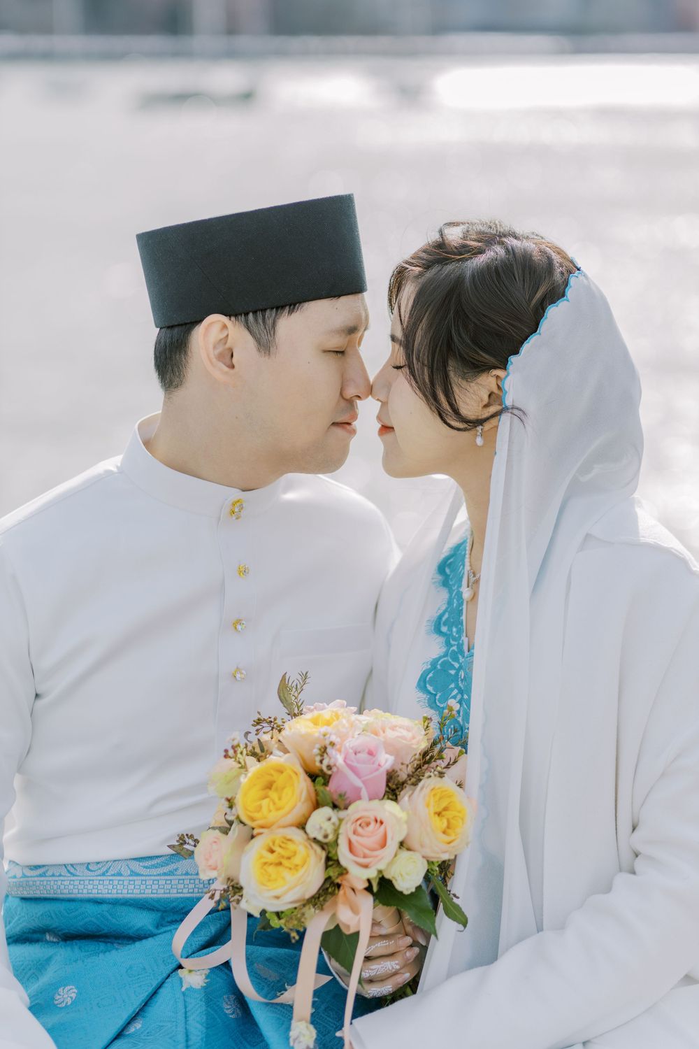 Romantic wedding portraits in traditional white and turquoise ceremonial attire with floral bouquet.