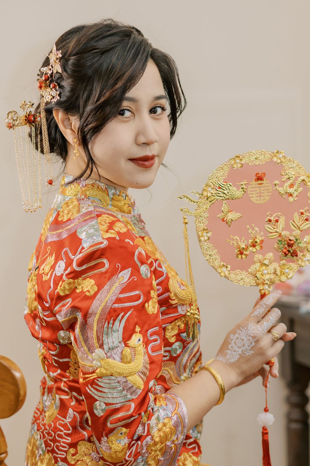 Traditional red qipao dress with intricate gold embroidery and oriental hair accessories.