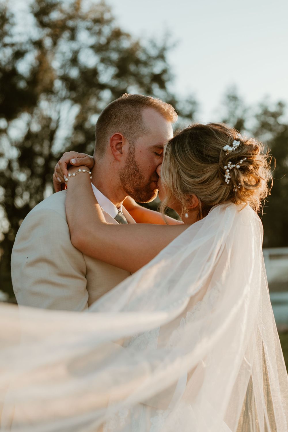 Romantic sunset wedding photos showing intimate moments between newlyweds with flowing veil.