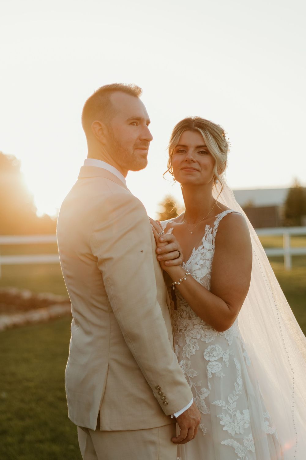 A romantic sunset wedding portrait shows a couple embracing outdoors in formal attire.