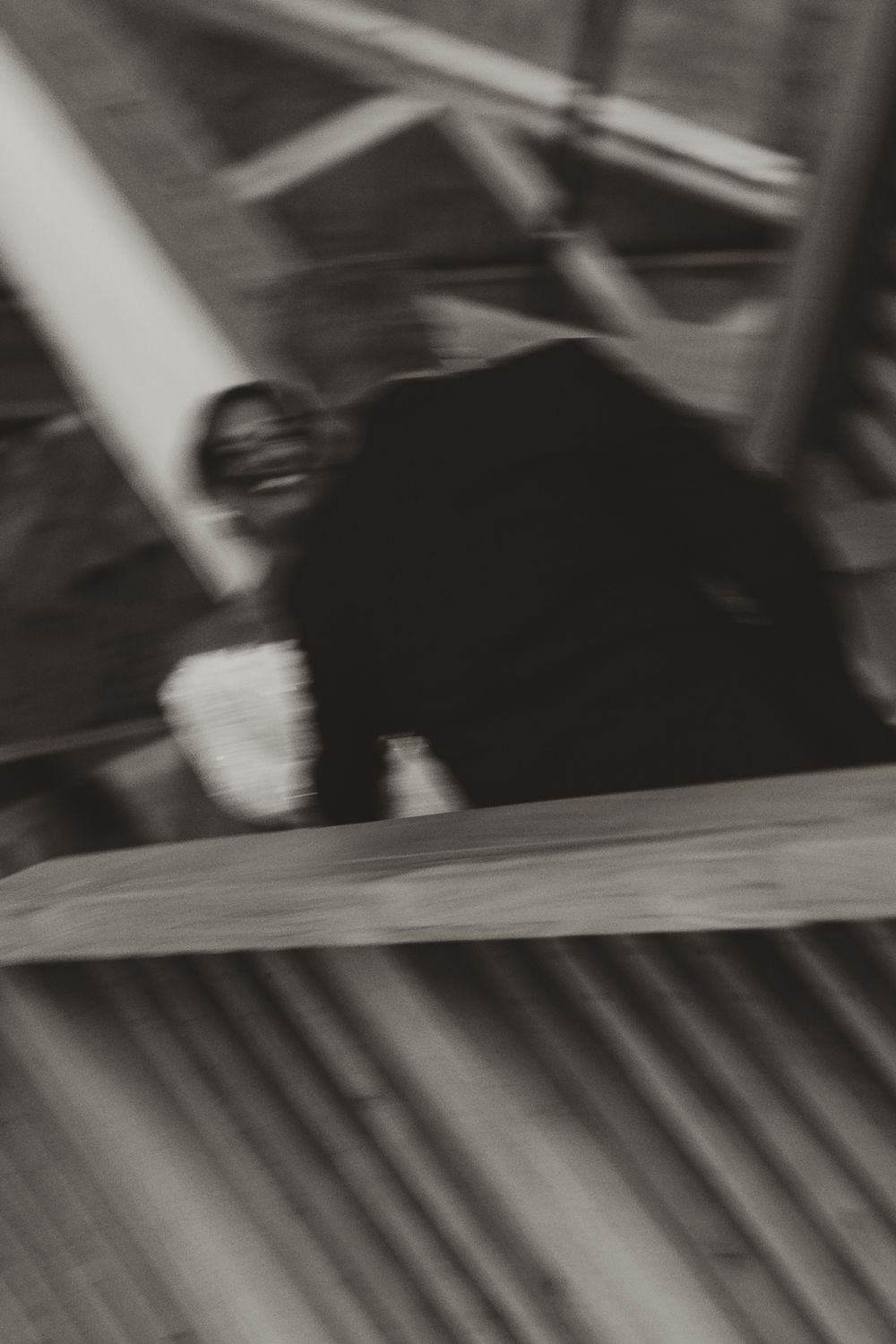A black and white motion-blurred abstract photograph showing diagonal lines and shapes in a dynamic pattern.