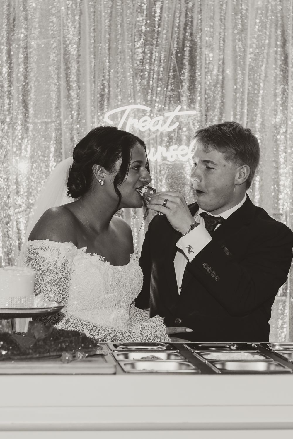 A series of wedding photos showing a couple feeding each other cake at their reception in front of a sparkly backdrop.