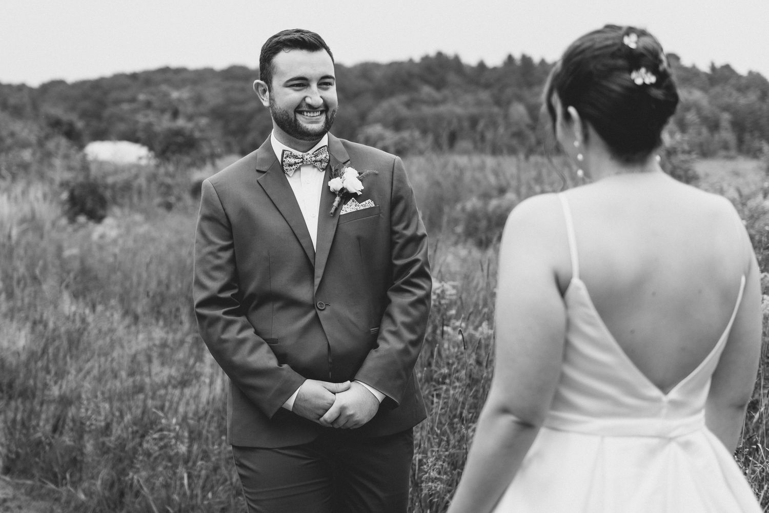 Black and white photo of a first look wedding moment between newlyweds in a scenic outdoor field.