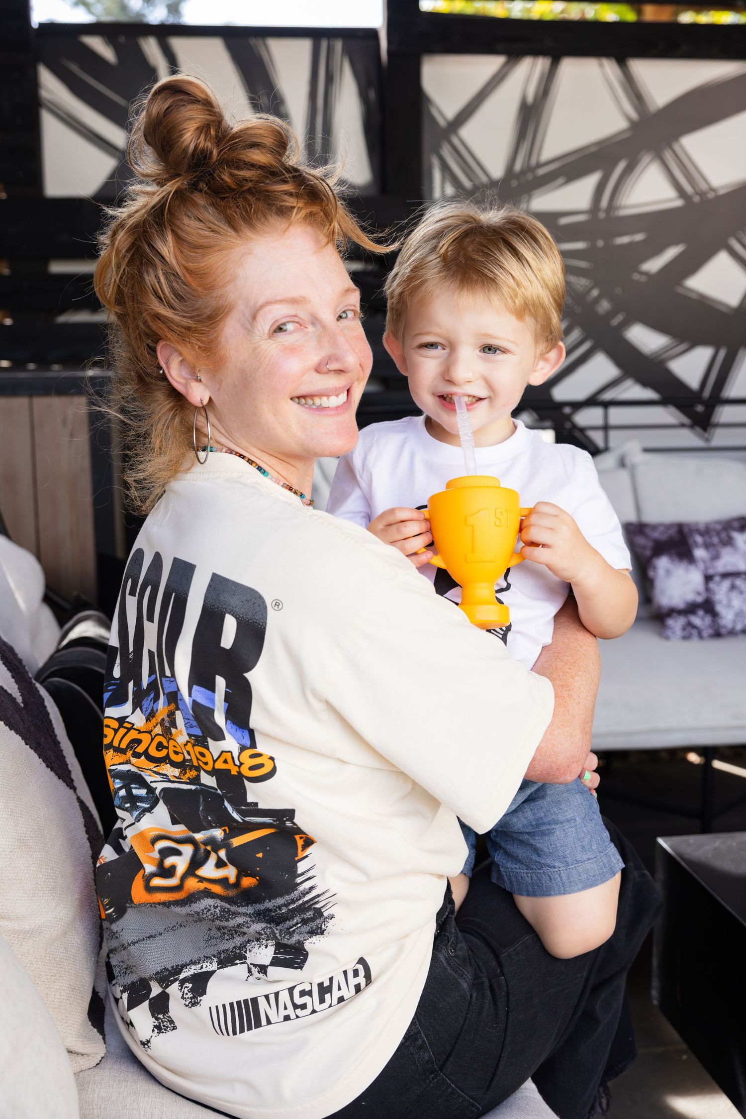 A happy moment shared between parent and child holding a yellow cup in a modern interior setting.