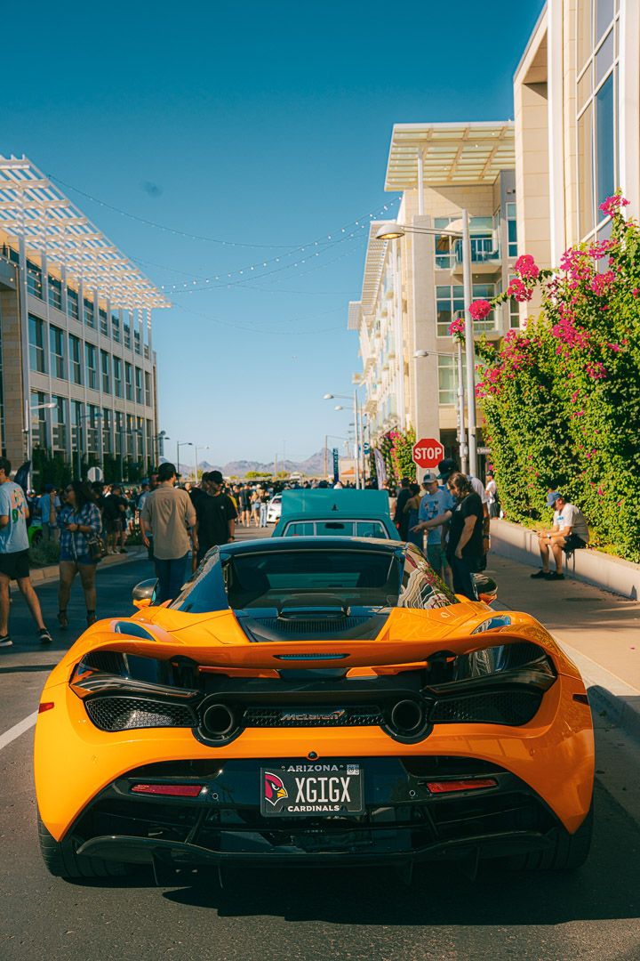 Rear view of an orange McLaren sports car showcasing its distinctive aerodynamic design and dual exhaust system.