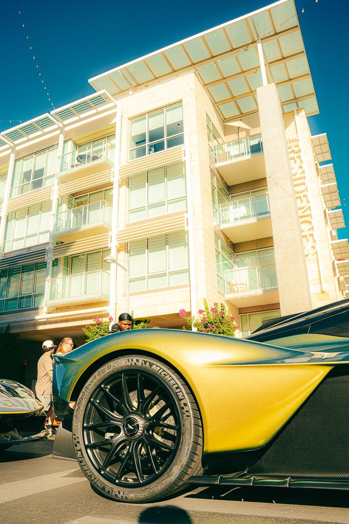 Low-angle shots of a sleek yellow supercar parked in front of a modern apartment building with sunlit architecture.