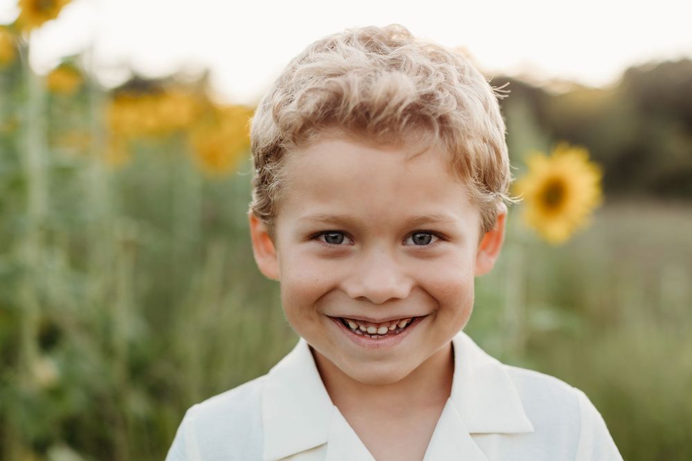 Natural outdoor portraits in a sunflower field with warm evening light.