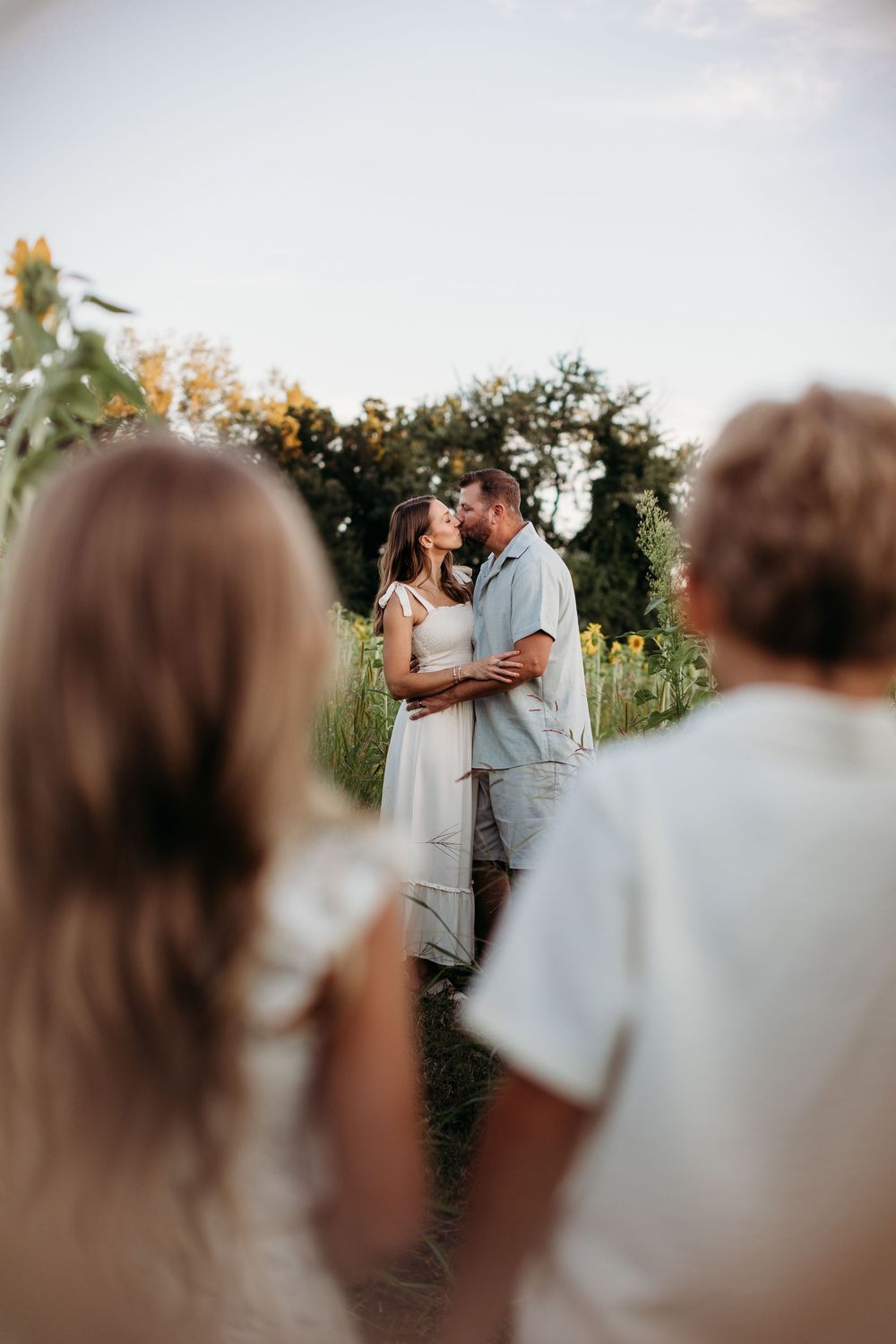 Intimate moment shared between two people in a sunflower field during golden hour.