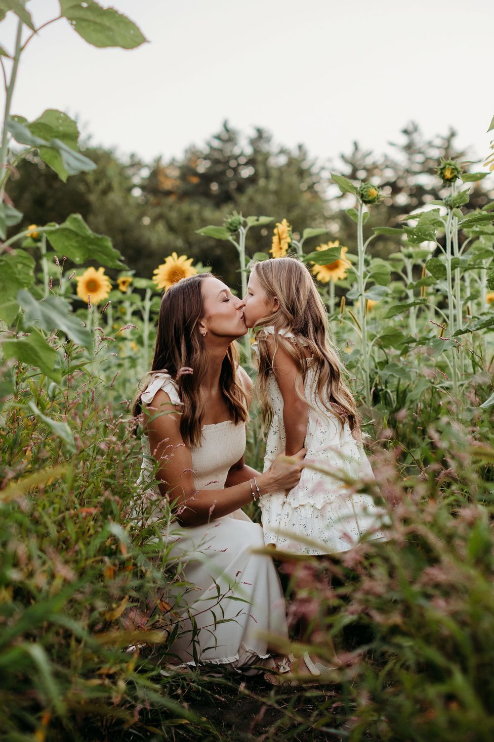Two people sharing a sweet moment while sitting in a blooming sunflower field.