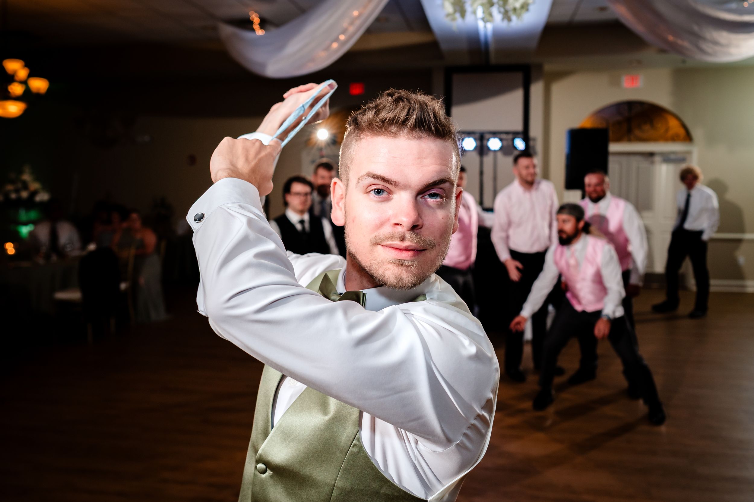 Wedding party members dance and celebrate on the reception dance floor.