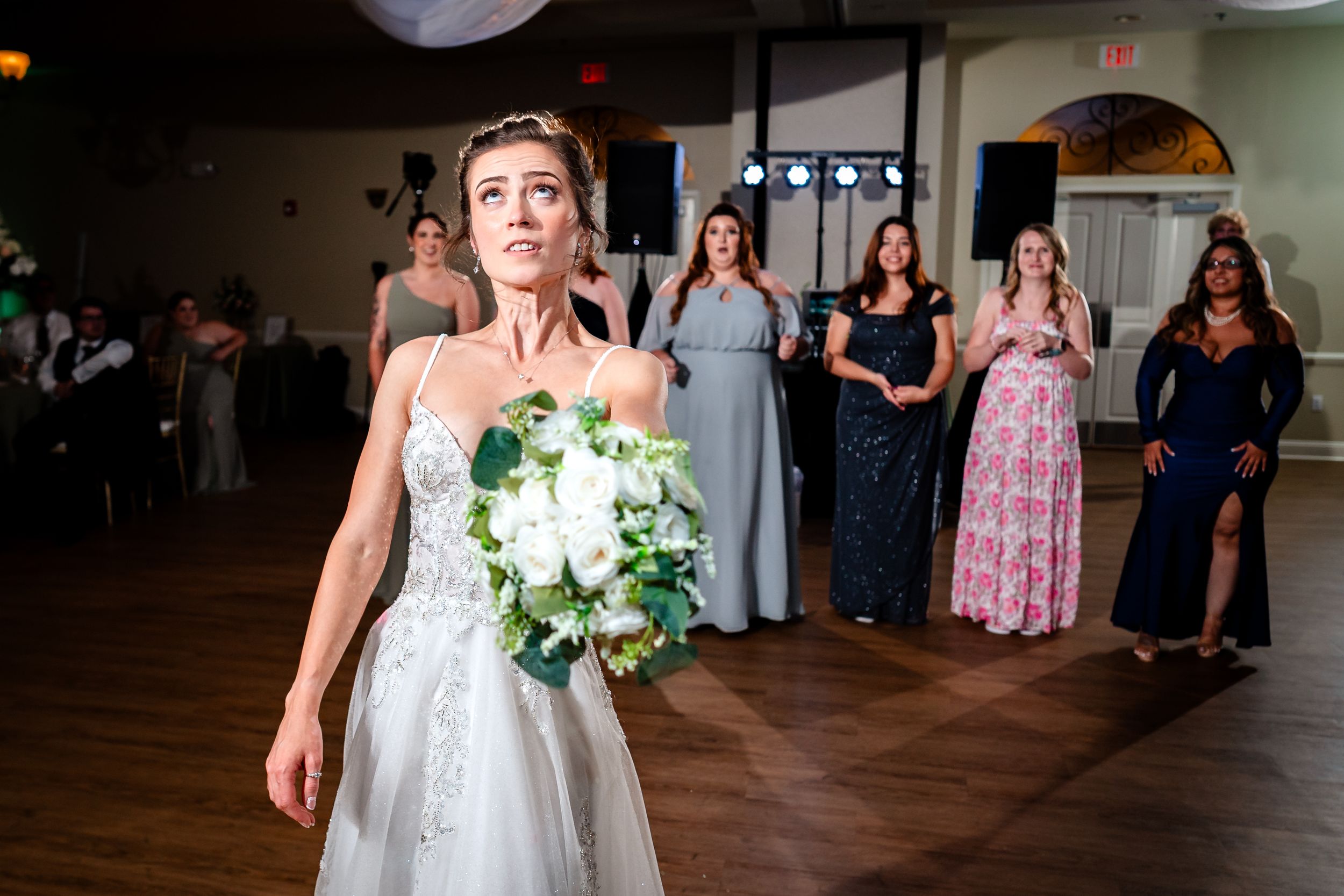 Wedding party members in sage green dresses walk across the dance floor.