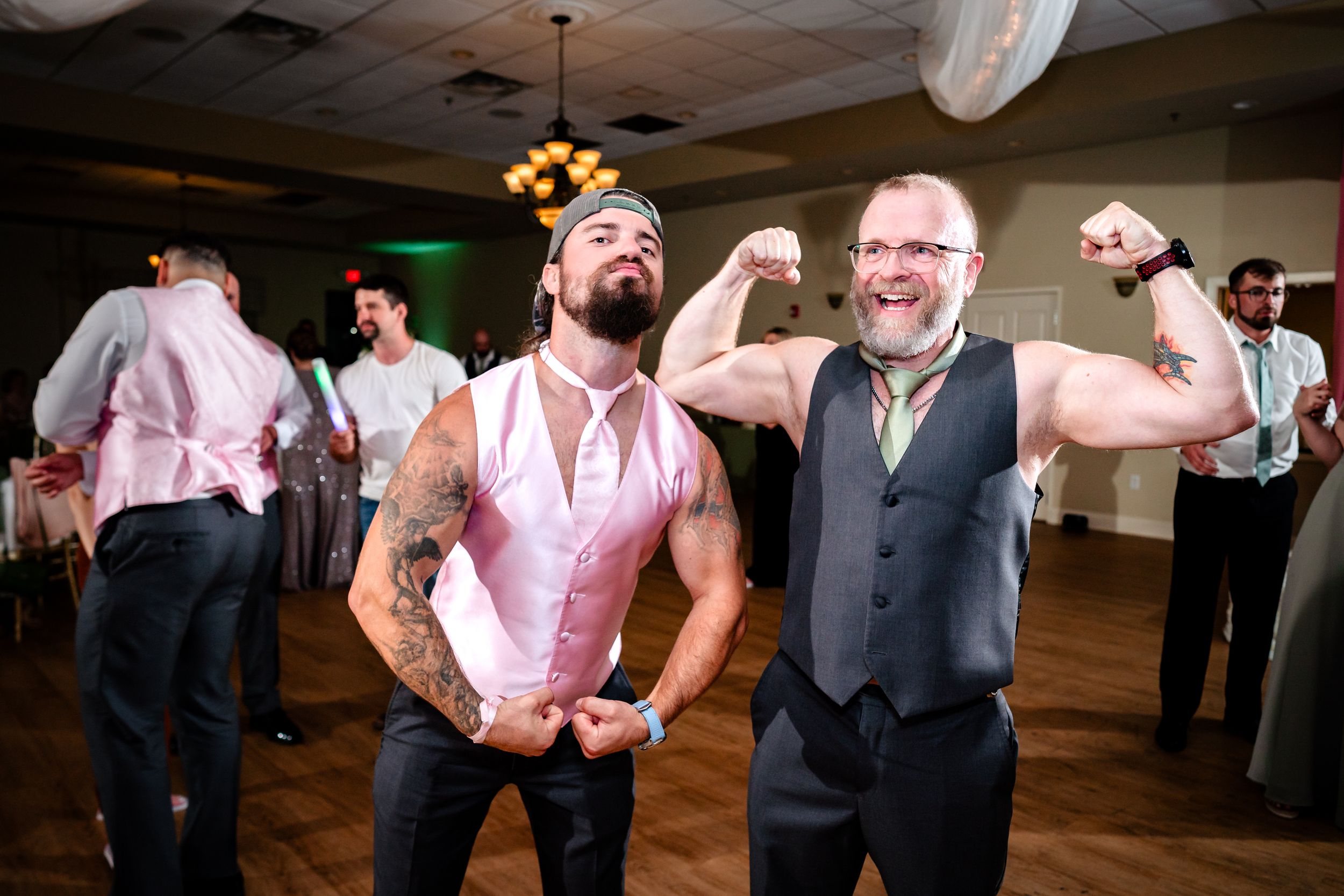Wedding party members in pink and gray attire dancing and celebrating.