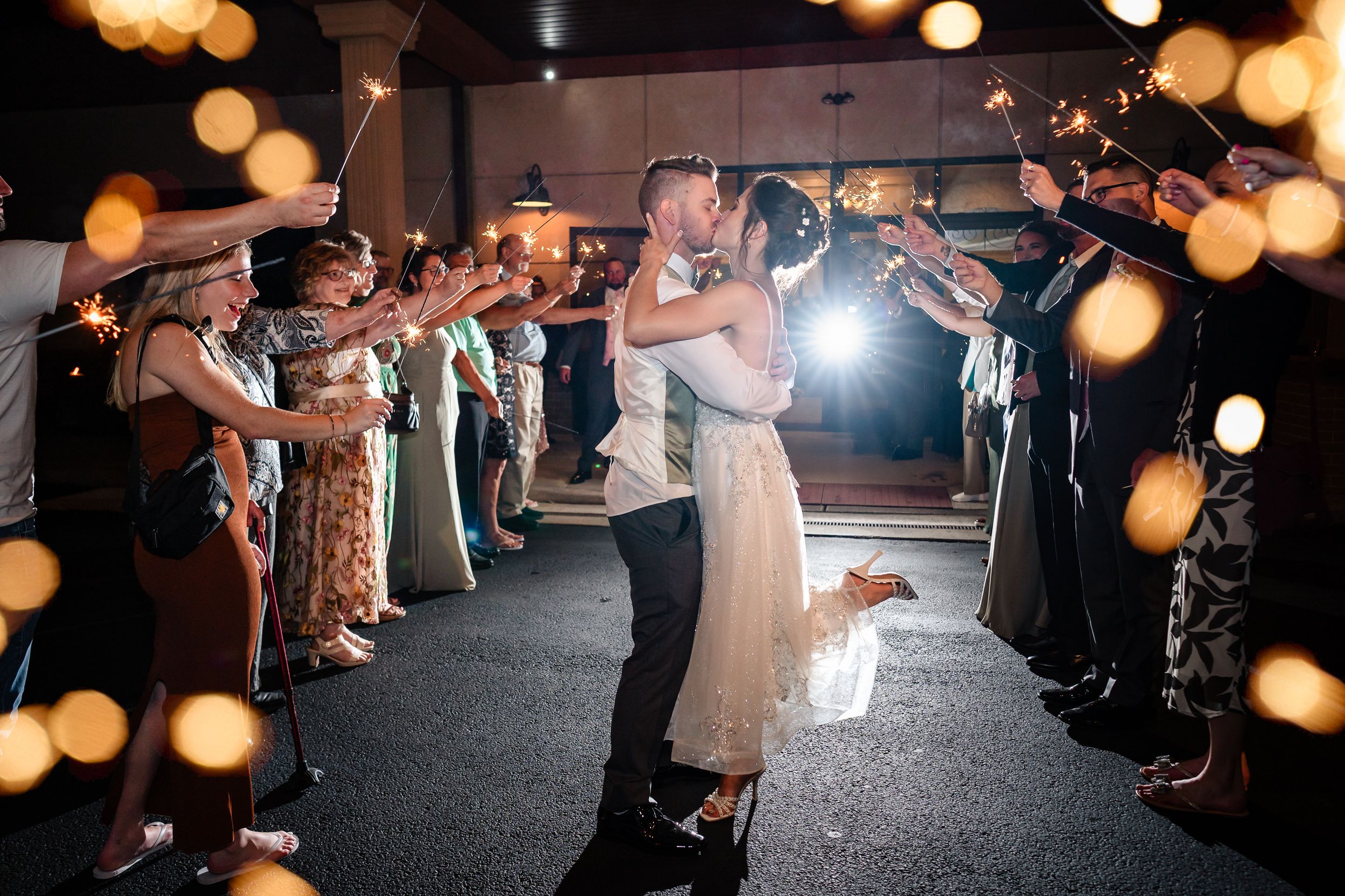 Wedding reception exit with guests holding sparklers creating a magical light tunnel.