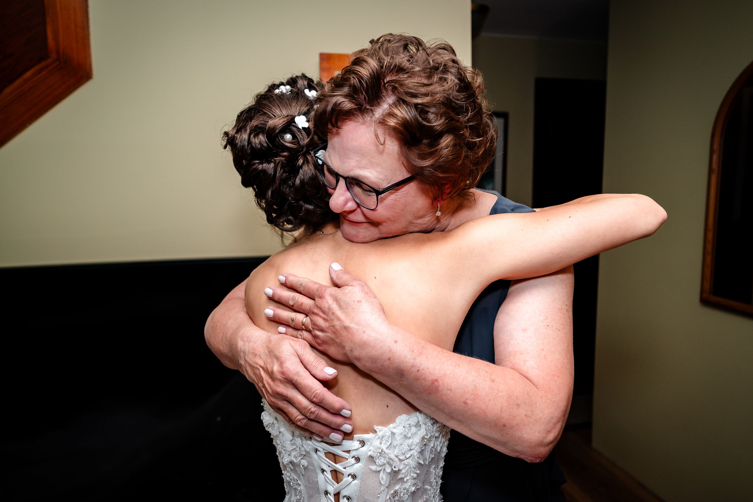 A tender emotional moment shared between a bride in a white dress and her loved one during a wedding day.