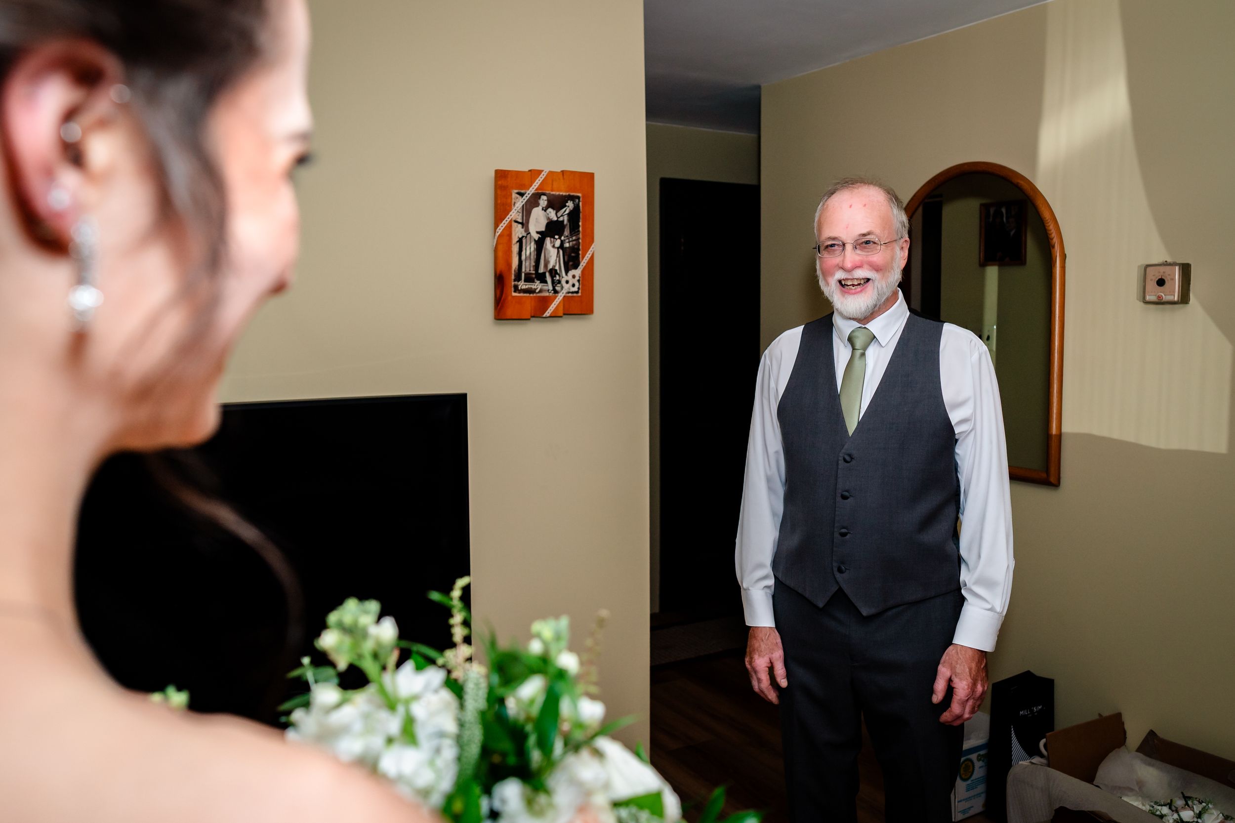 A wedding party getting ready in a room with gray bridesmaid dresses and floral decorations.