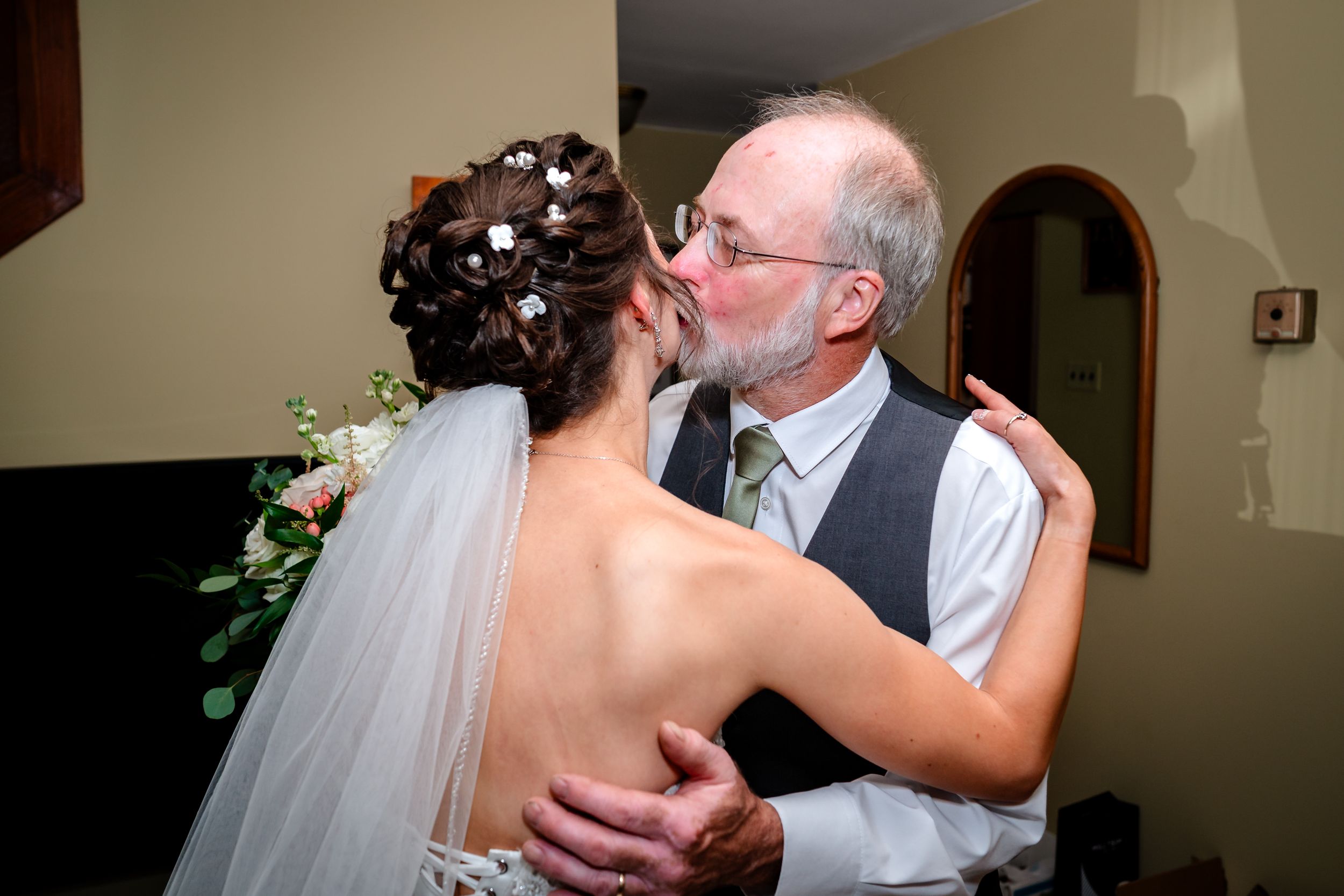 A heartfelt moment shared during wedding preparations in a warmly lit indoor setting.