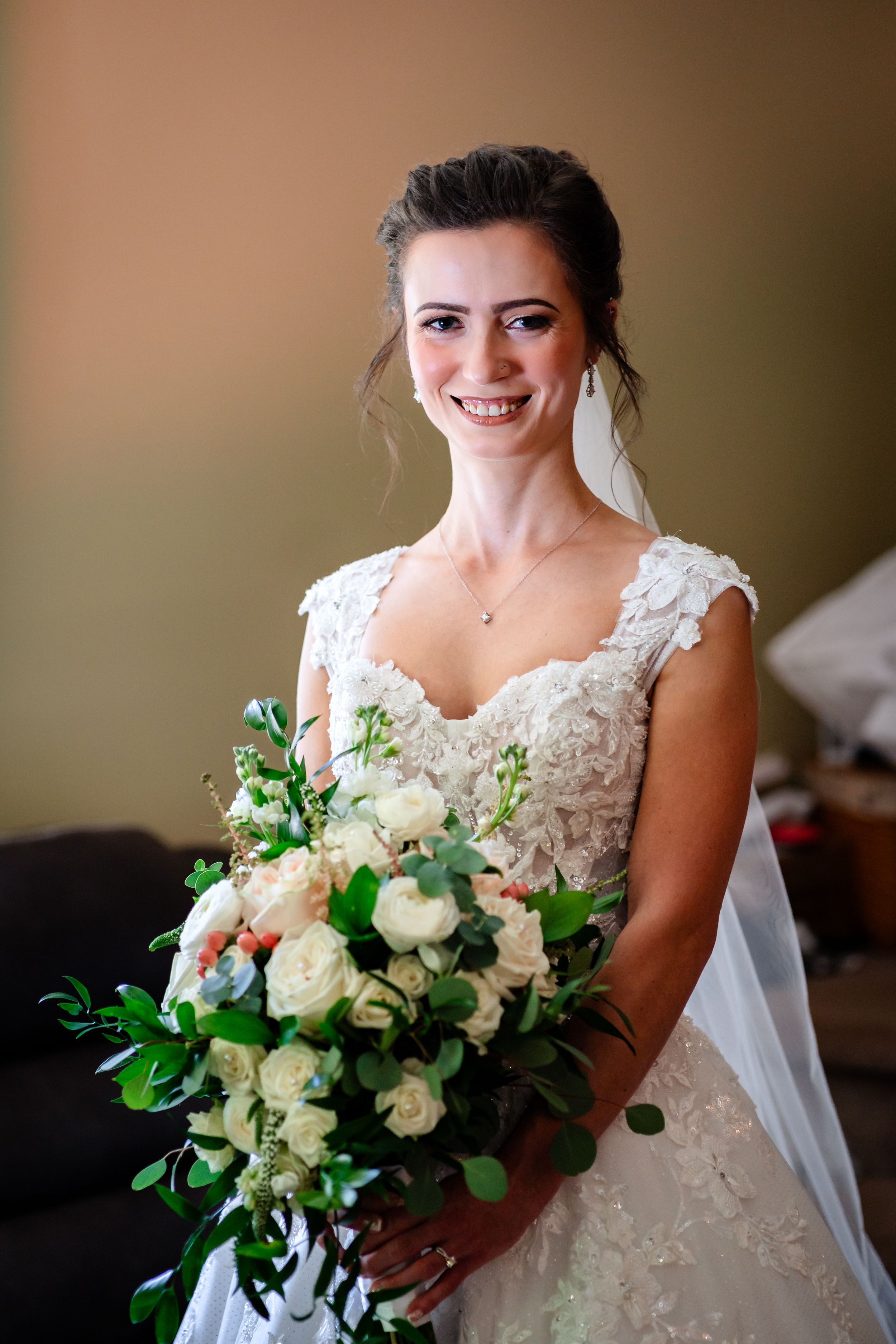 Bride holding a stunning white and green floral bouquet in her lace wedding gown.