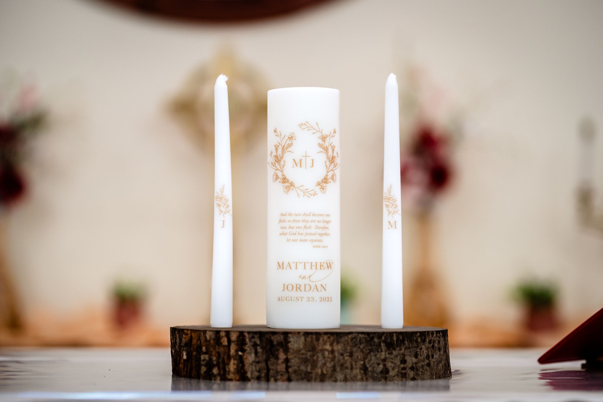 White wedding candles and decorative elements arranged on a rustic wooden table for a ceremony.