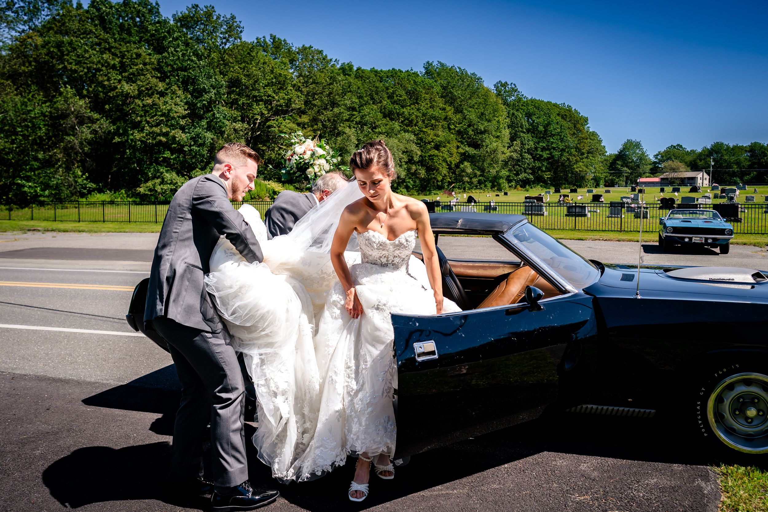 Classic black limousine parked outdoors for a wedding celebration on a sunny day.