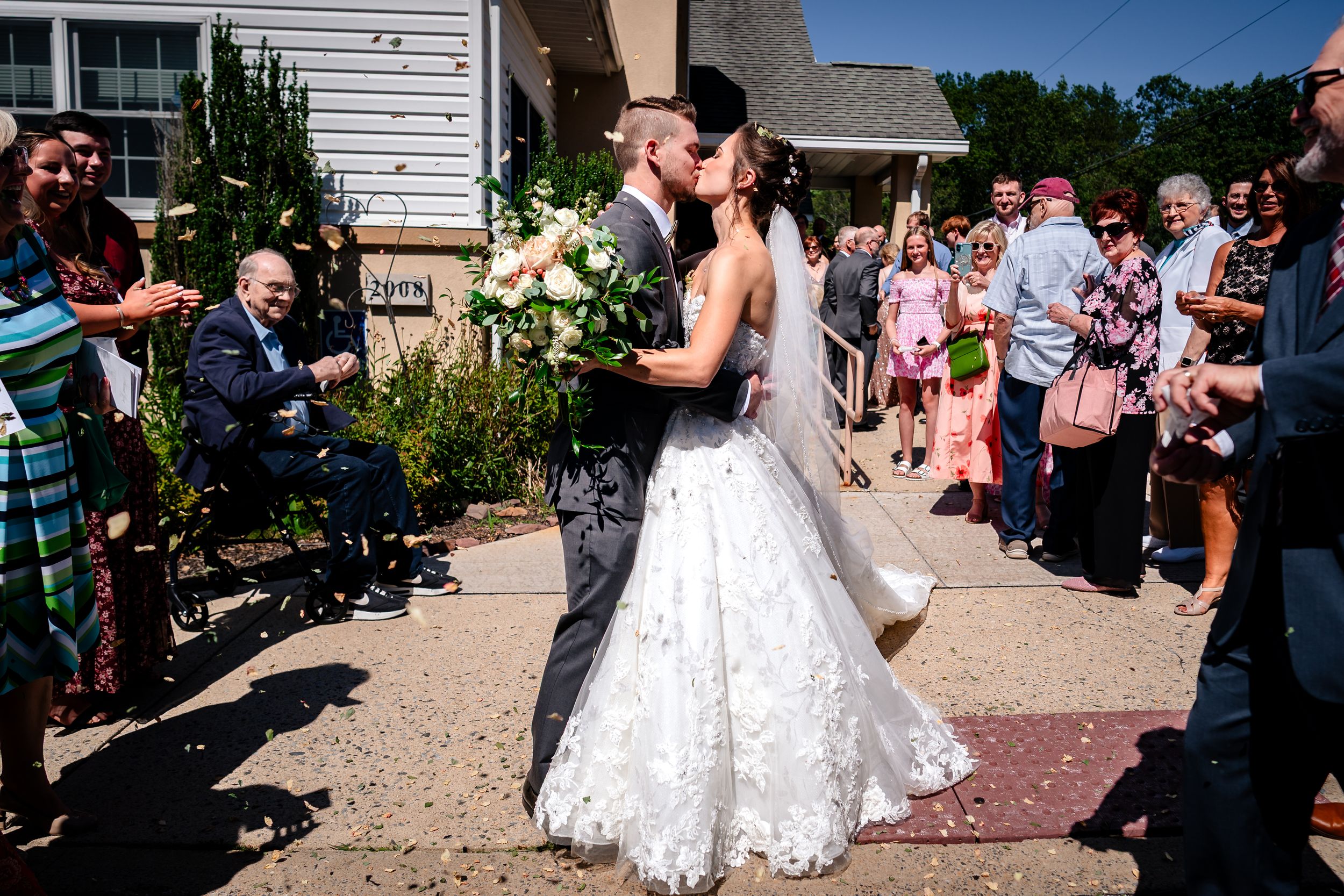 Outdoor wedding exit with guests celebrating as couple walks through.