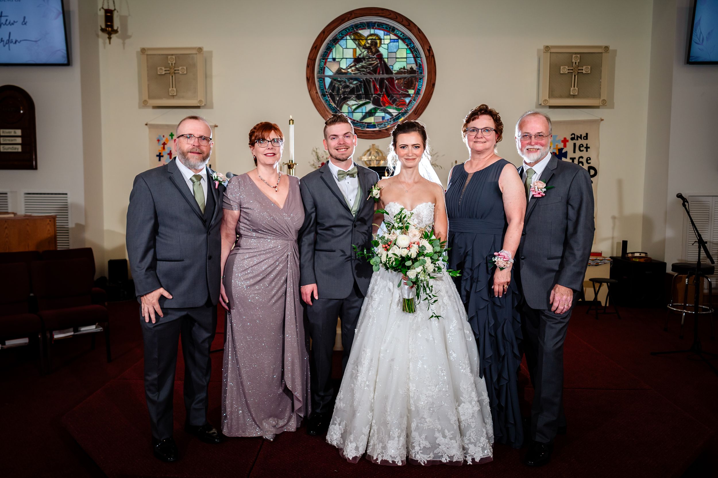 Wedding party poses for formal group photo in church sanctuary.