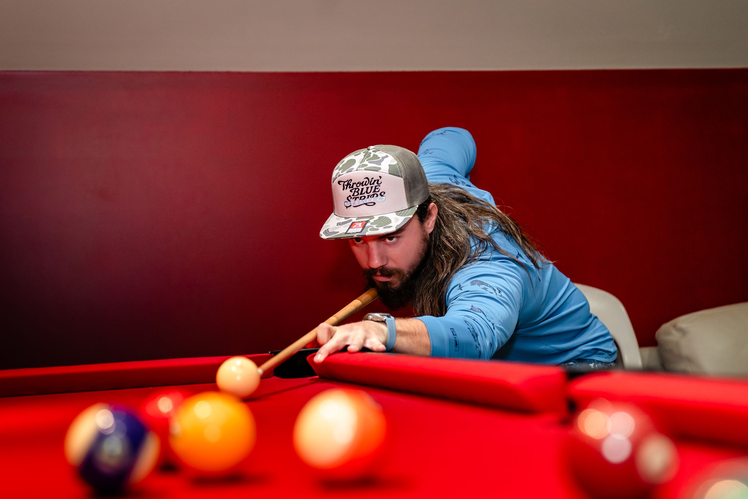 Players leaning over a red pool table taking shots during a game.