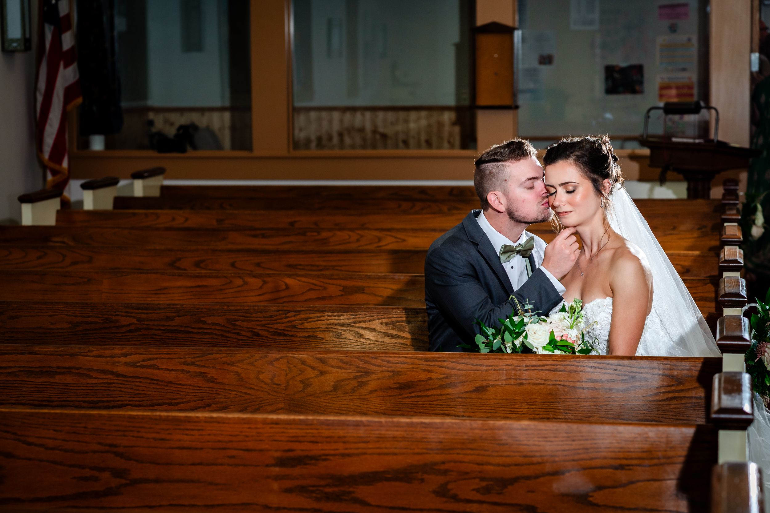 Romantic wedding couple shares an intimate moment in a rustic wooden venue setting.