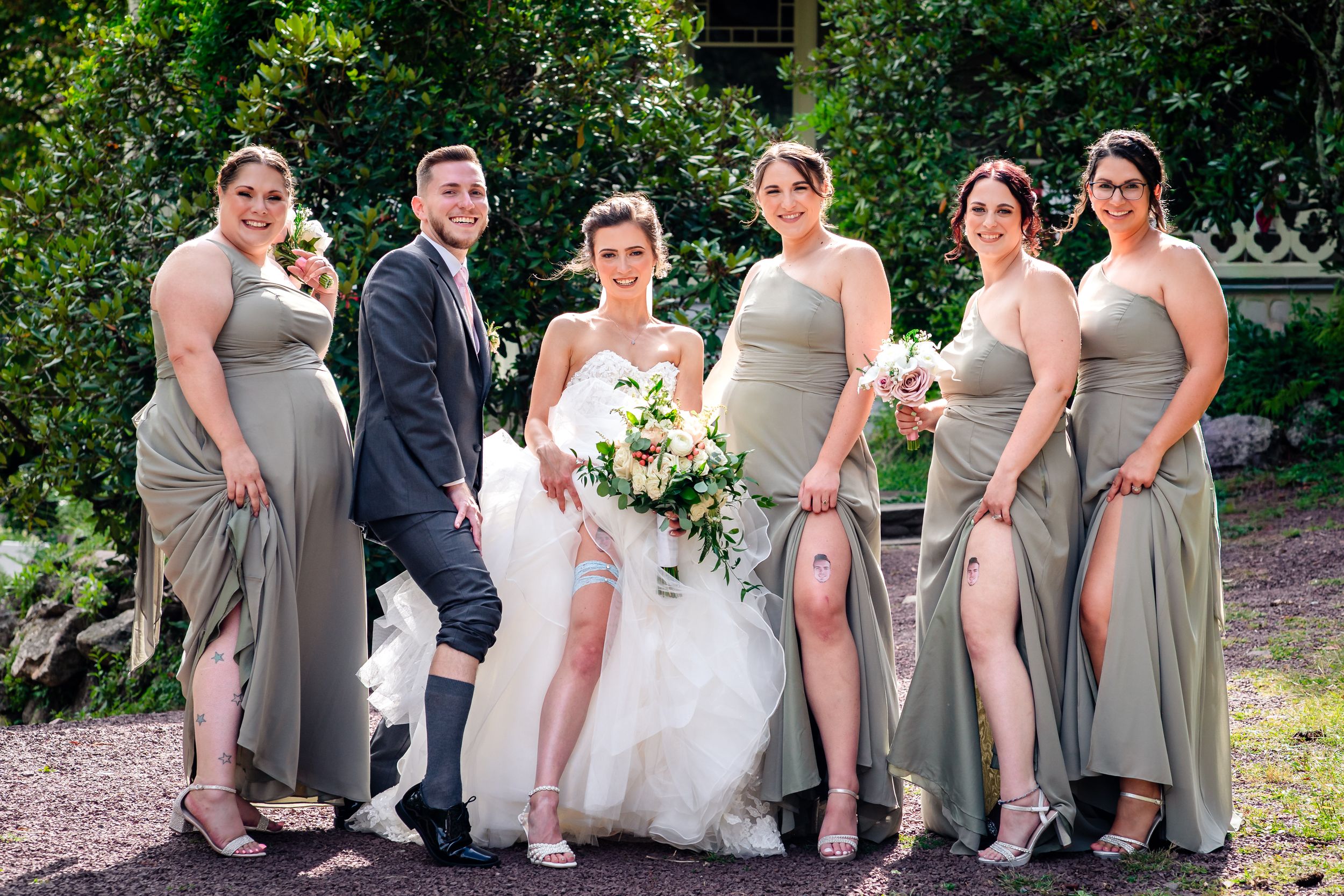 Wedding party in gray dresses and suits relaxes on garden path.