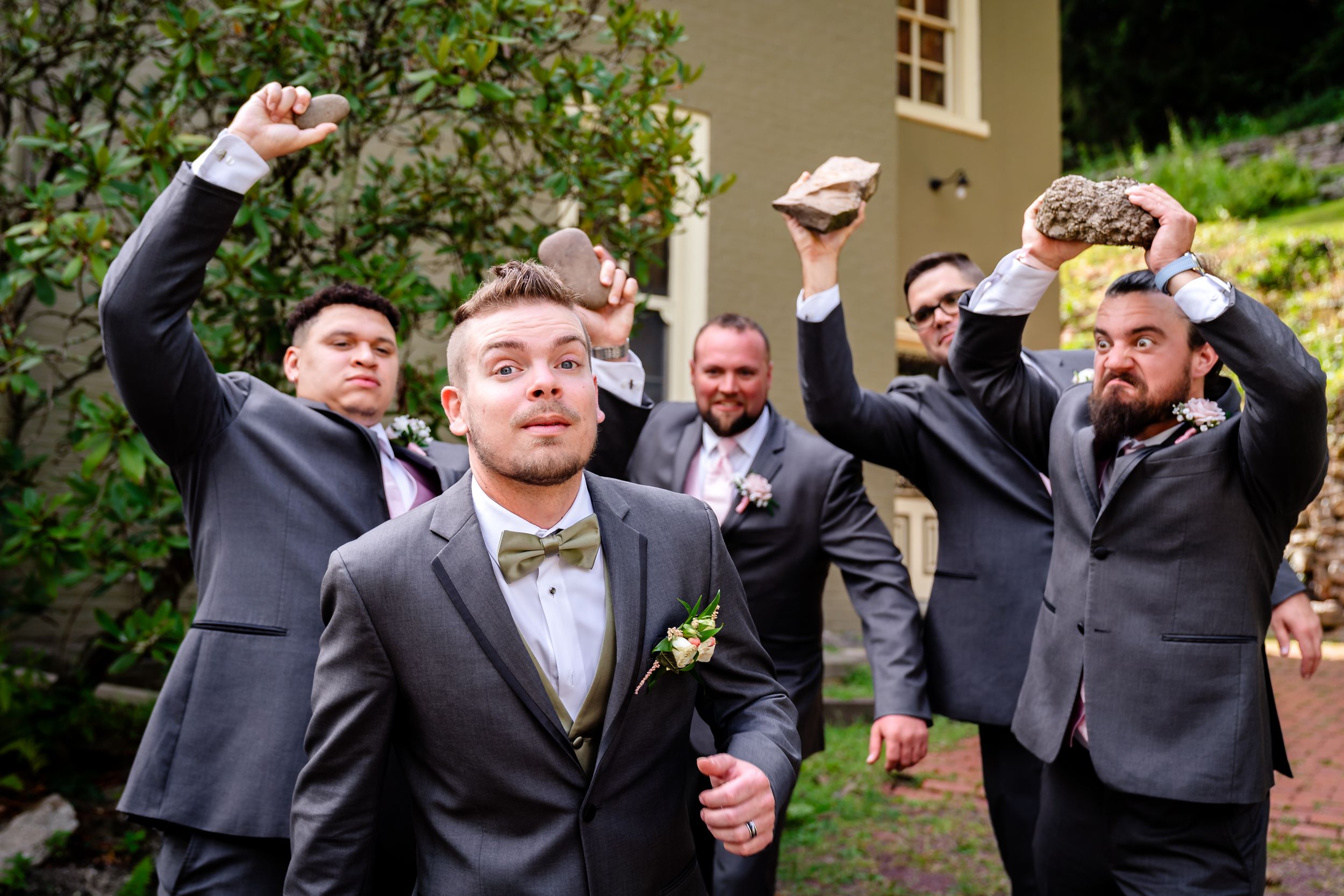 Groomsmen in formal attire share drinks and laughter during wedding celebration.