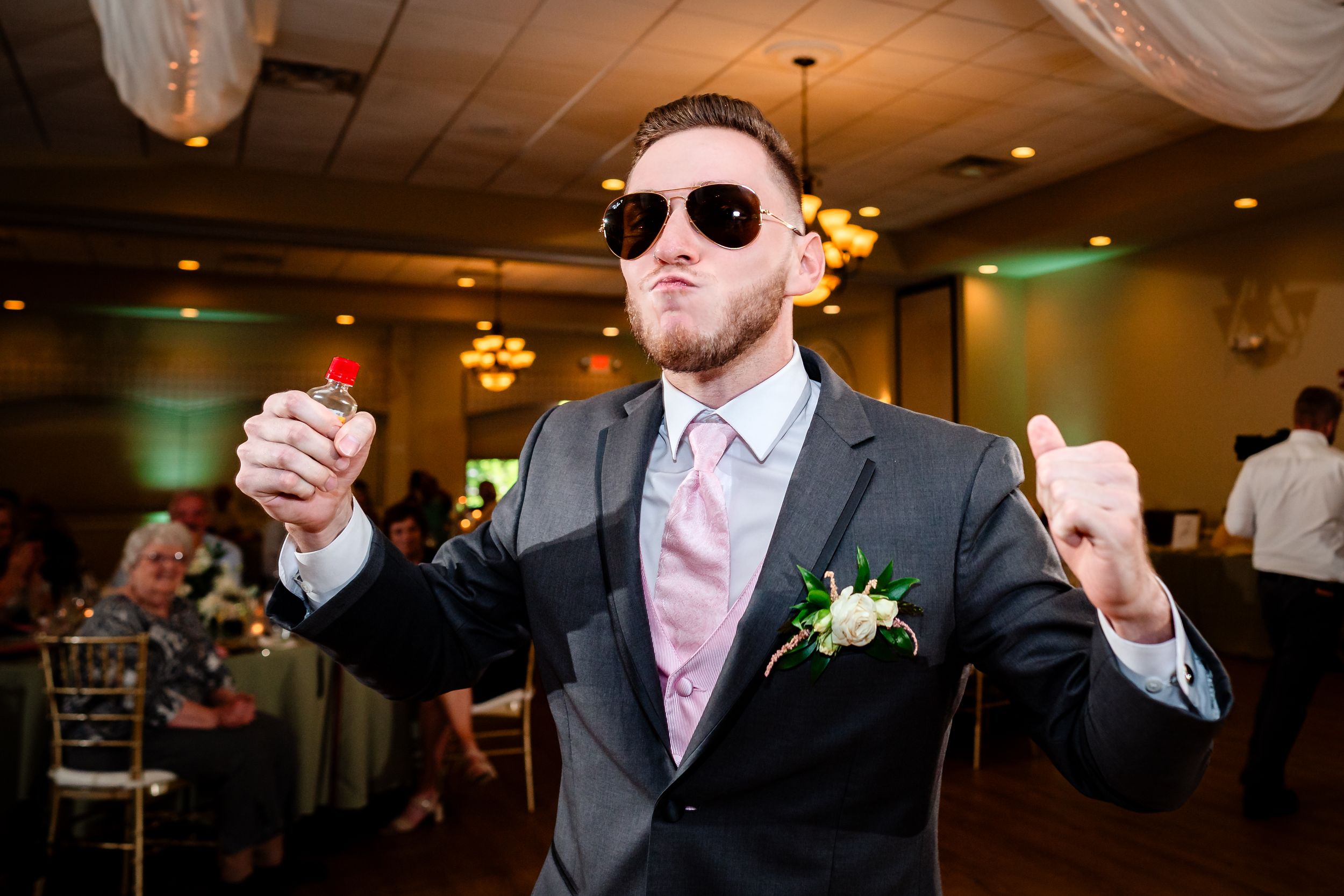 Wedding reception guests dancing and celebrating in an indoor venue with mood lighting.